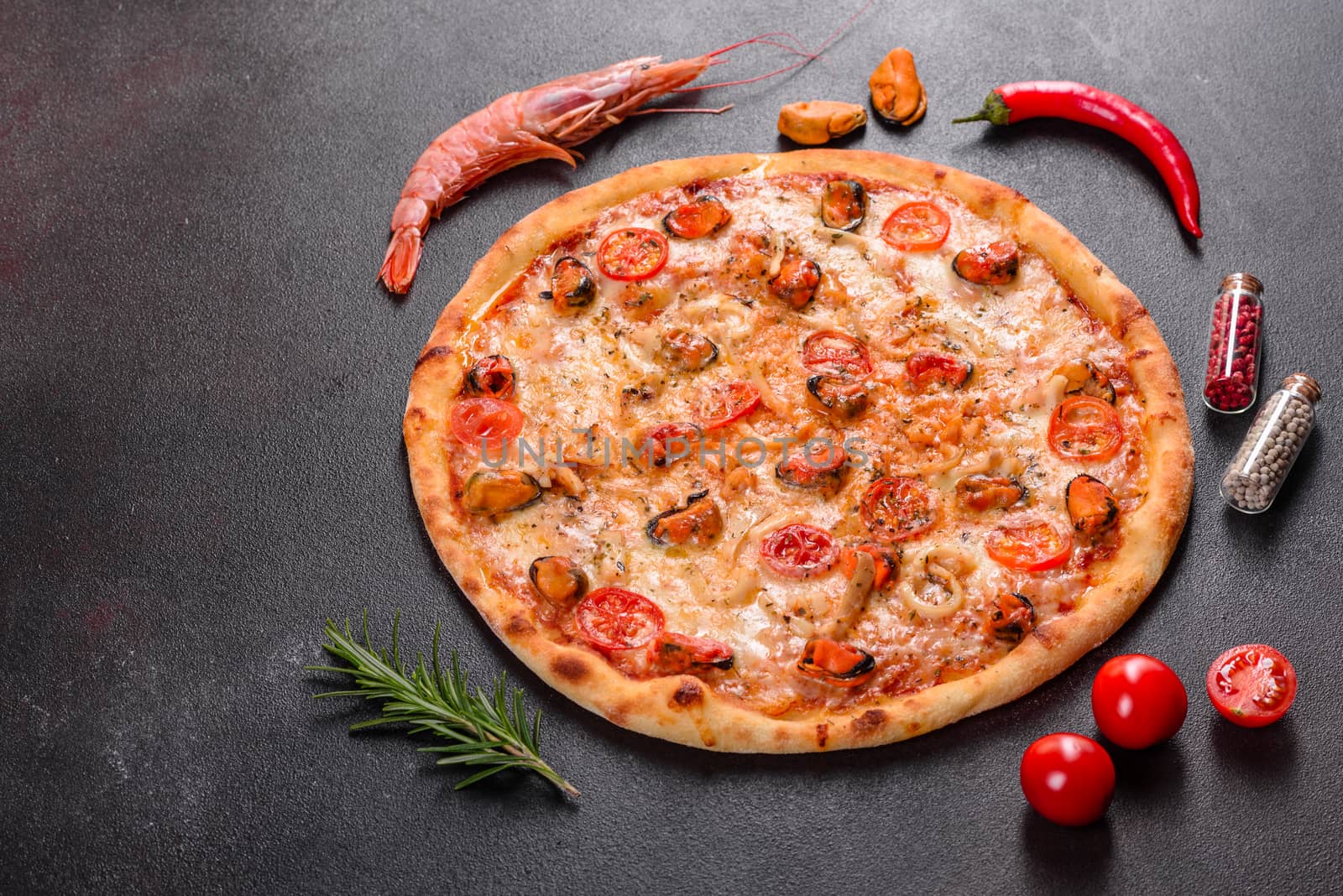 Seafood Italian pizza with shrimp, squid, mussels, fresh herbs and mozzarella on a
dark background. Tasty sliced pizza with seafood and tomato on a concrete background