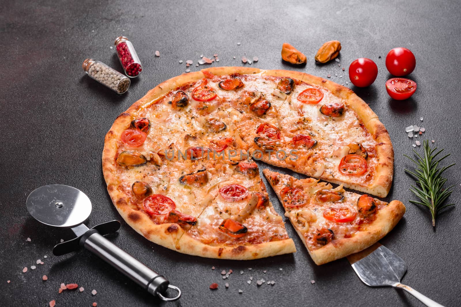 Seafood Italian pizza with shrimp, squid, mussels, fresh herbs and mozzarella on a
dark background. Tasty sliced pizza with seafood and tomato on a concrete background
