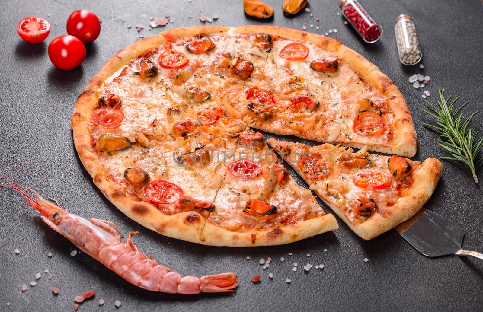Seafood Italian pizza with shrimp, squid, mussels, fresh herbs and mozzarella on a
dark background. Tasty sliced pizza with seafood and tomato on a concrete background