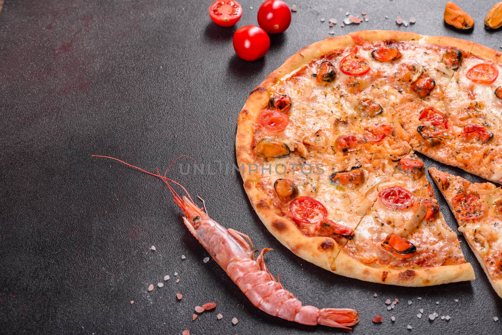 Seafood Italian pizza with shrimp, squid, mussels, fresh herbs and mozzarella on a
dark background. Tasty sliced pizza with seafood and tomato on a concrete background