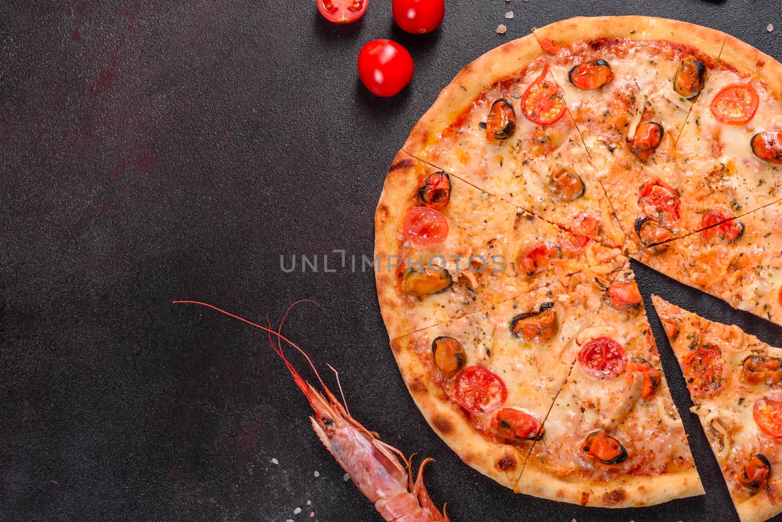 Seafood Italian pizza with shrimp, squid, mussels, fresh herbs and mozzarella on a
dark background. Tasty sliced pizza with seafood and tomato on a concrete background