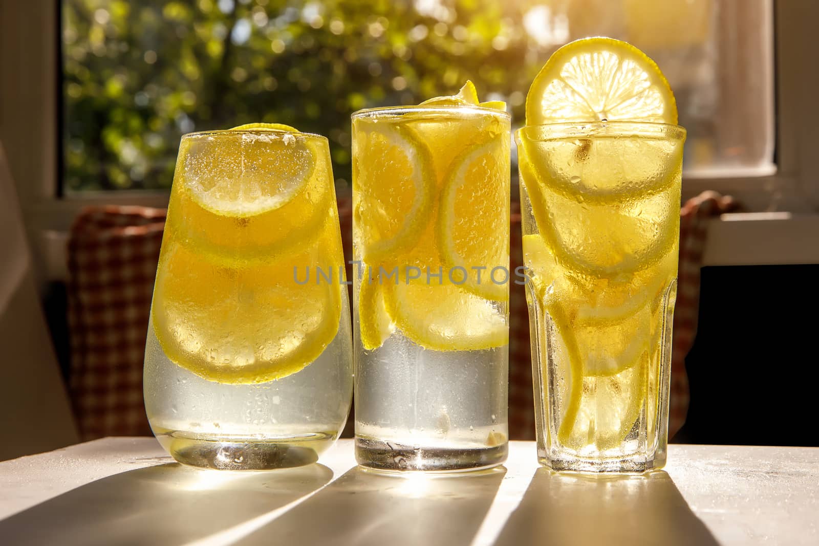 Glasses of lemonade with lemon on the sunny room background