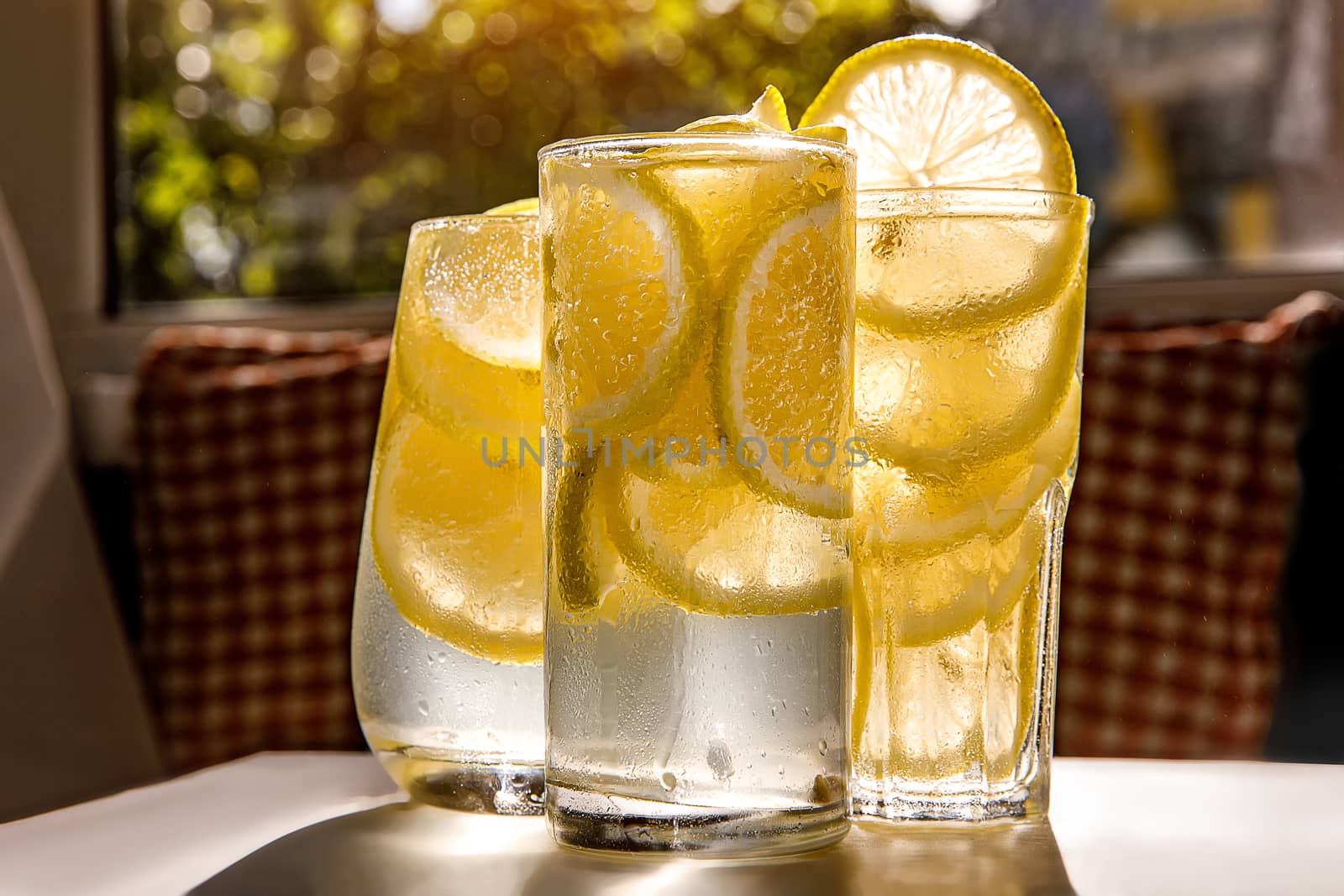 Glasses of lemonade with lemon on the sunny room background