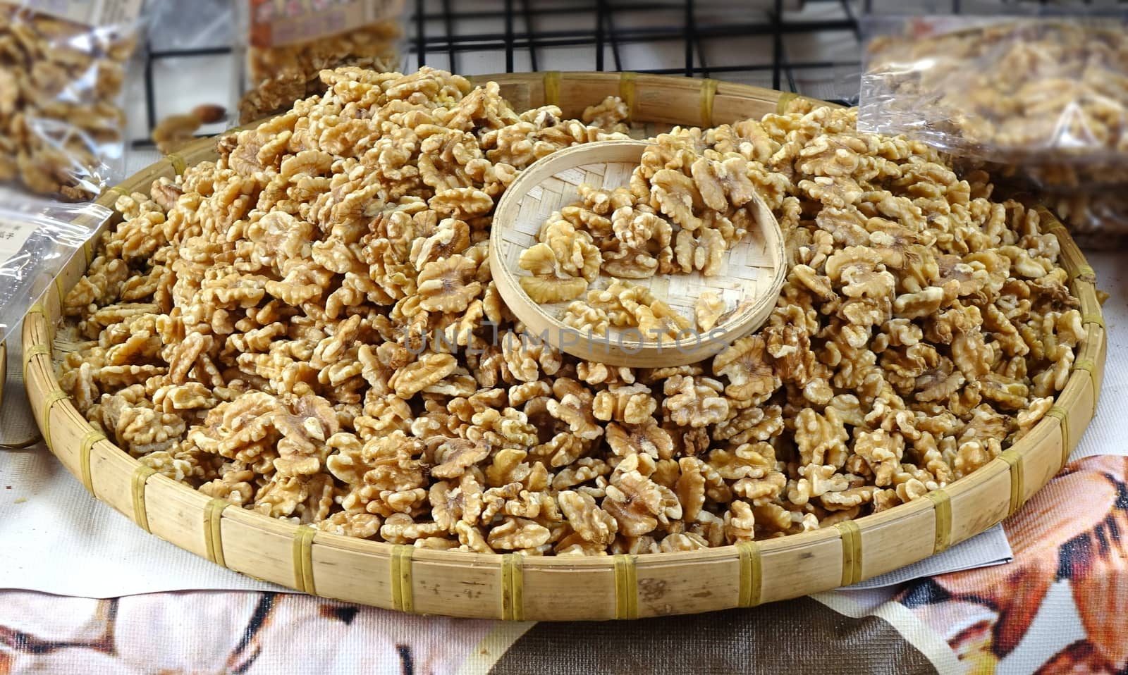 A street vendor sells fresh walnuts in a bamboo tray