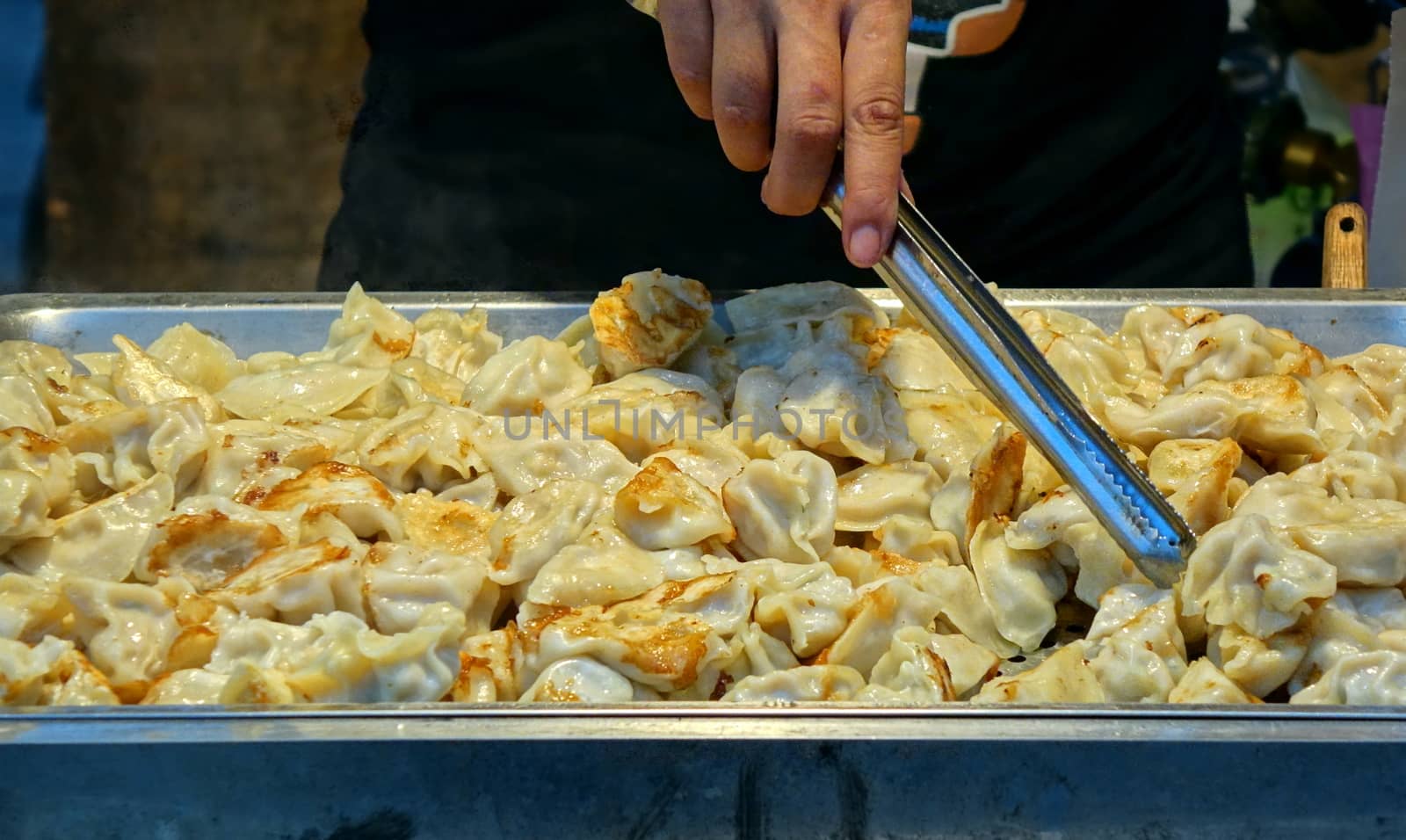 An outdoor vendor sells fried dumplings or pot-stickers
