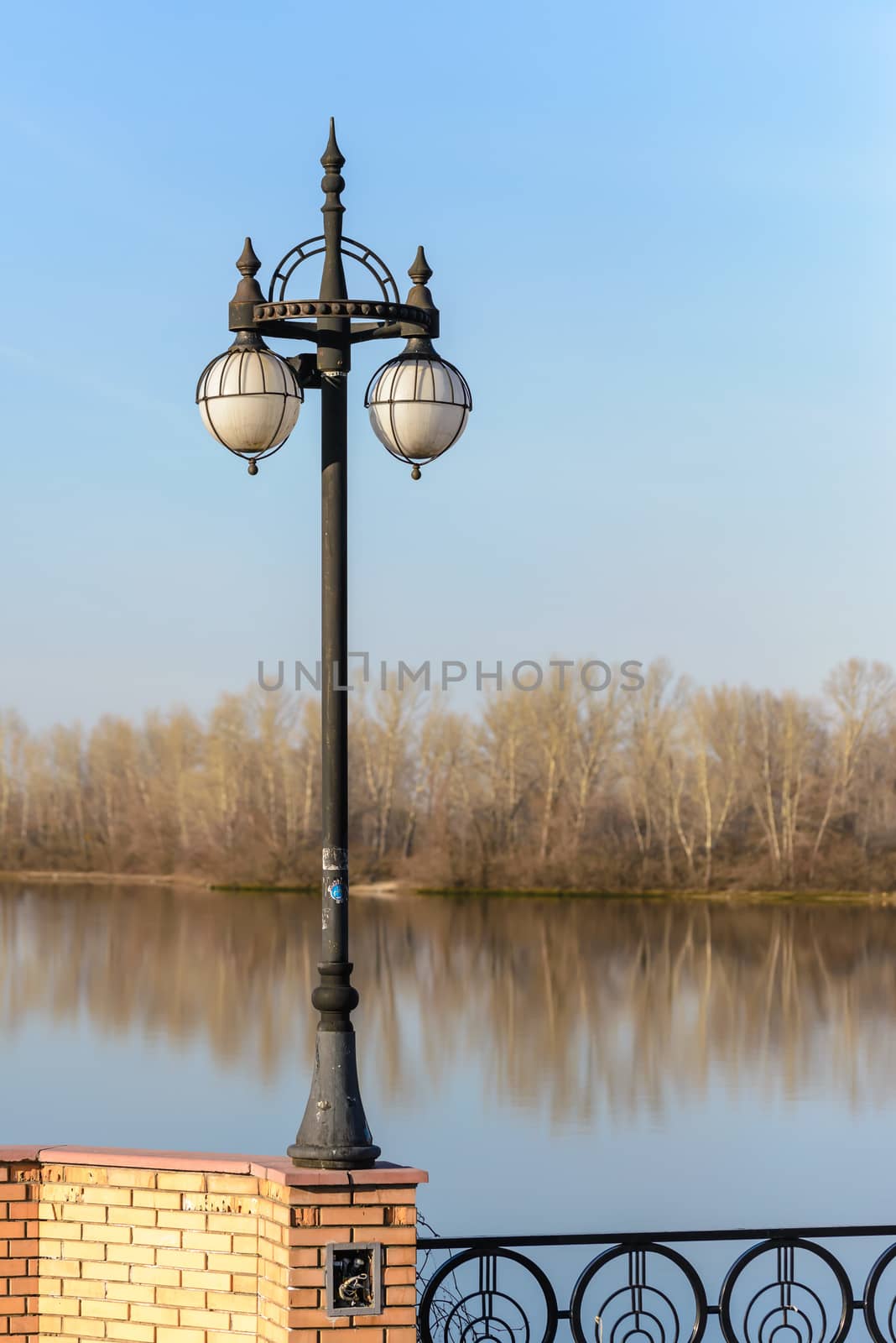 A street lamp close to the river with trees in the background