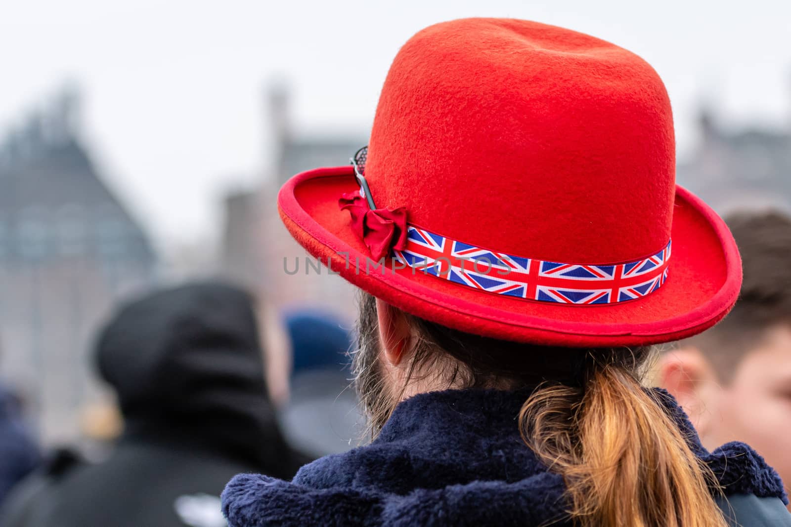 A man in a red hat with a British flag ribbon in a hat on a defocused London street background. Rear view by askoldsb