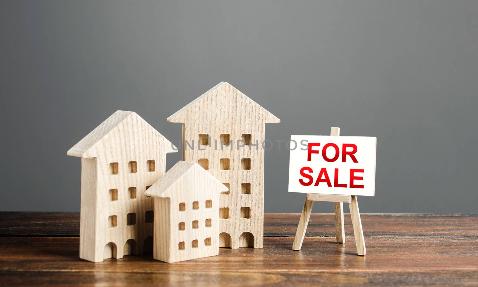Wooden figures of residential buildings and an easel sign labeled for sale. Buying and selling real estate, hot offers and property valuation. Smart investments and relocation. Good offer by iLixe48