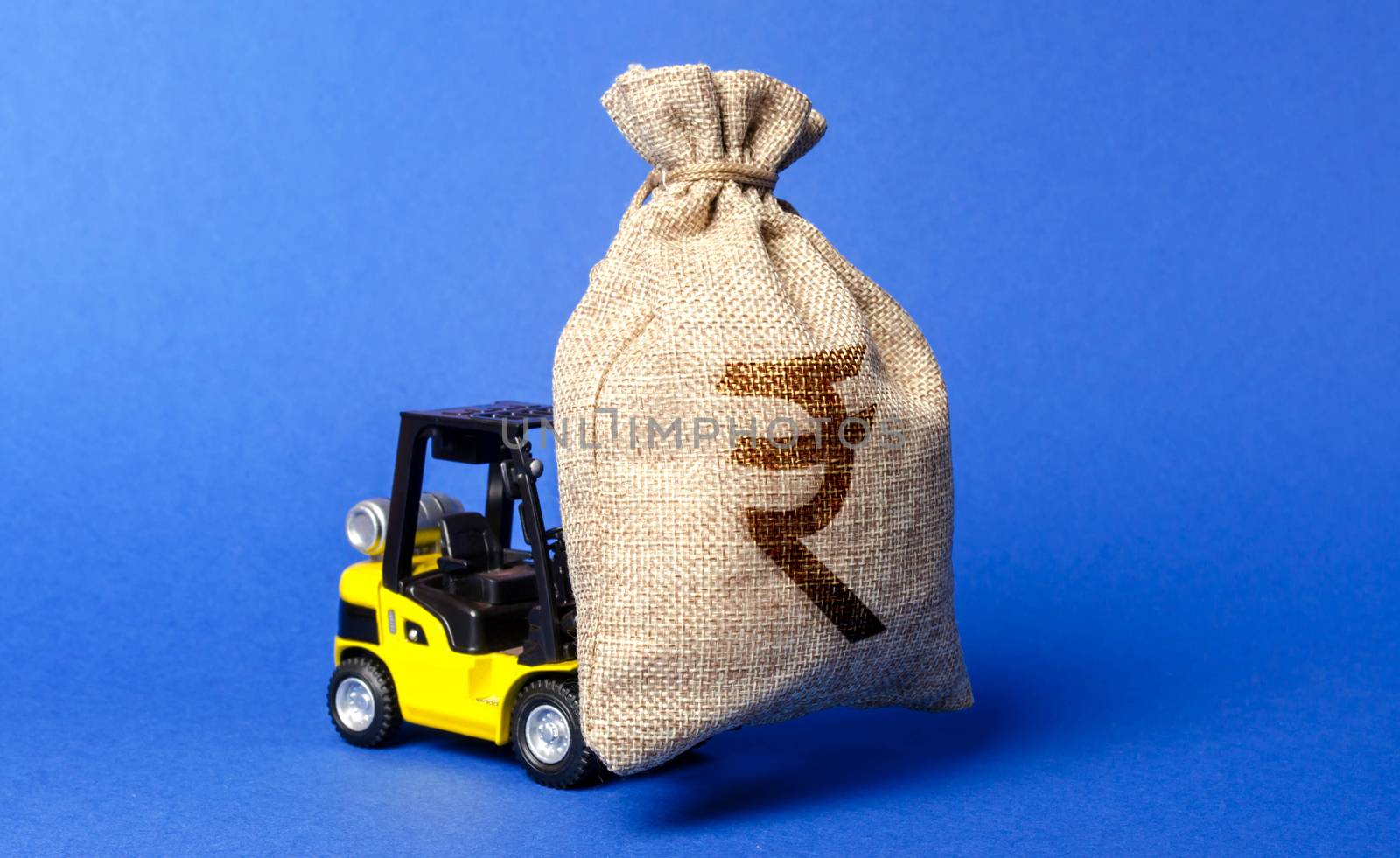 A forklift carries a huge money bag with the symbol of the Indian rupee. Budget and corruption, investment and economic growth. capital migration. Revenue profit. Superprofits, effective funds use