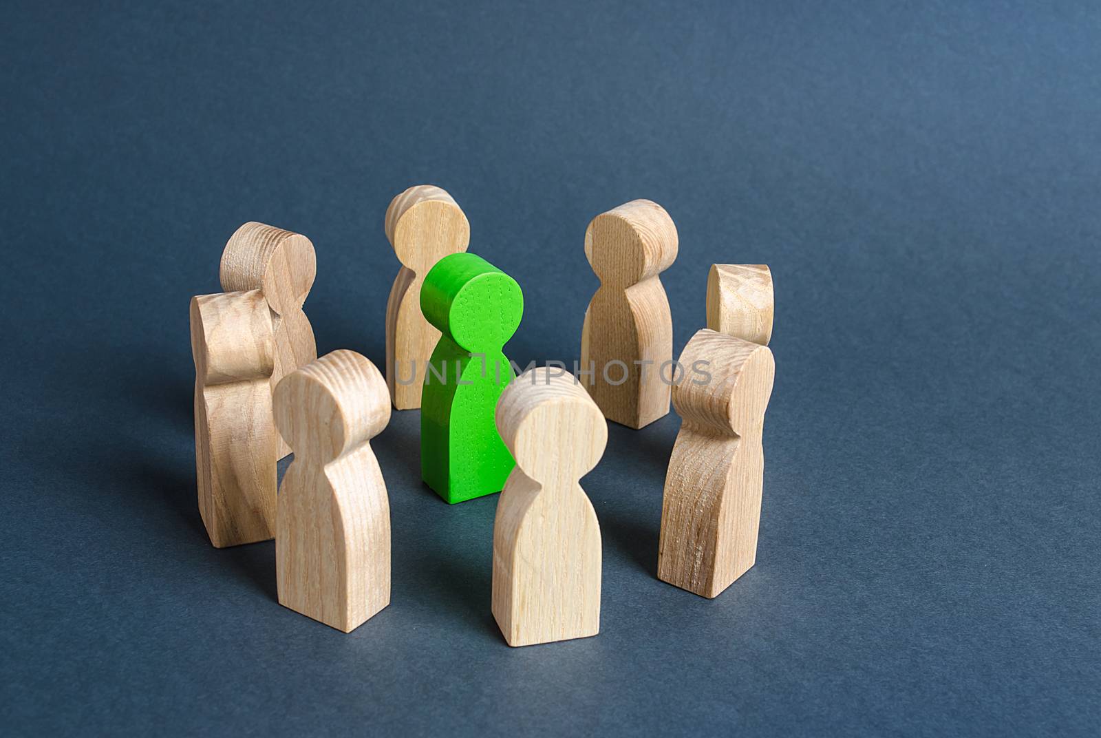 A green human figure is surrounded by a circle of people. Cooperation and collaboration. Fundraising and people around the idea. To unite like-minded persons. Leader and leadership skills.