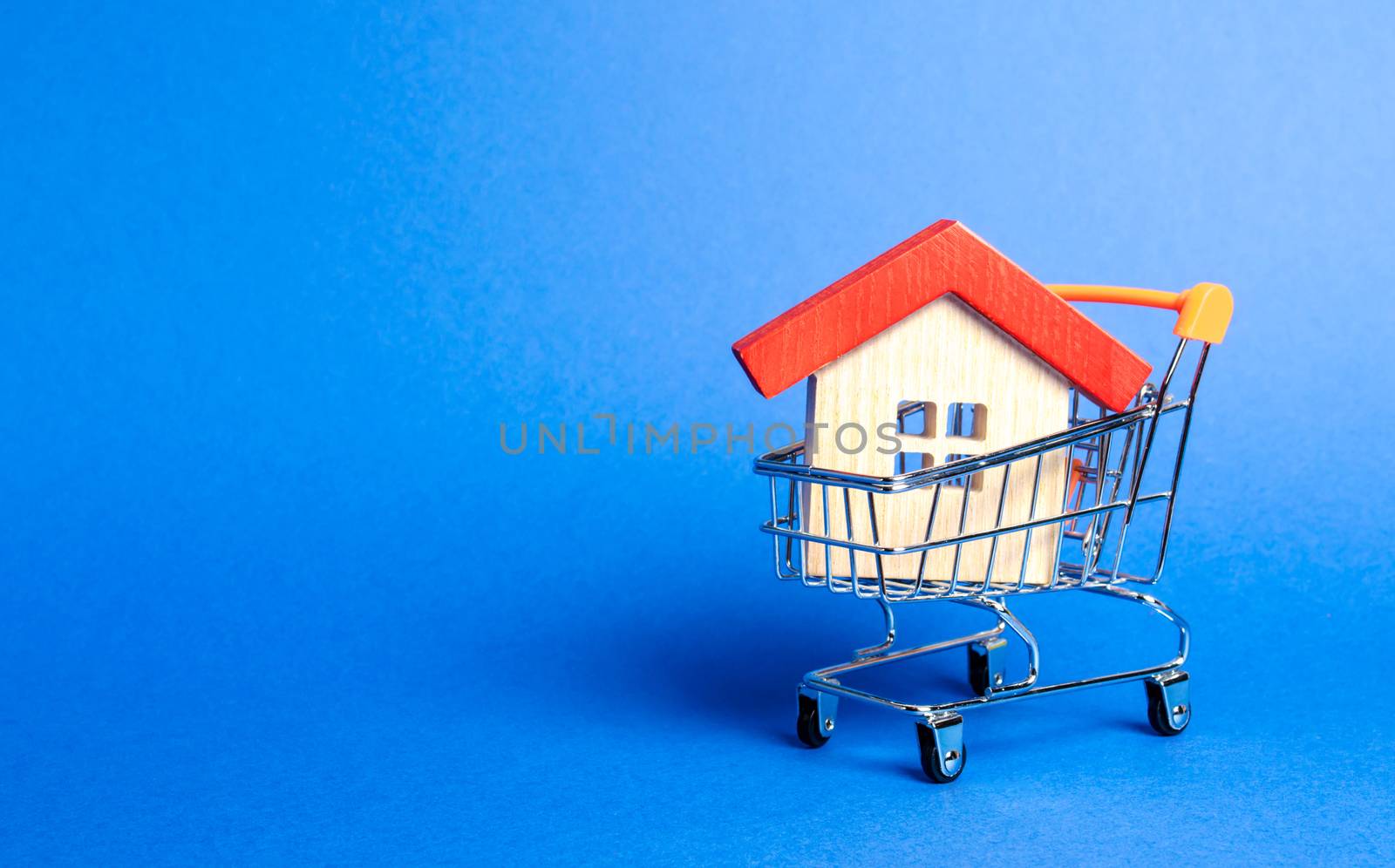 Wooden house in a Supermarket trading cart. The concept of buying a house or apartment. Affordable housing. Profitable and cheap loans for real estate. Buying a home. Mortgage and loan. Place for text by iLixe48