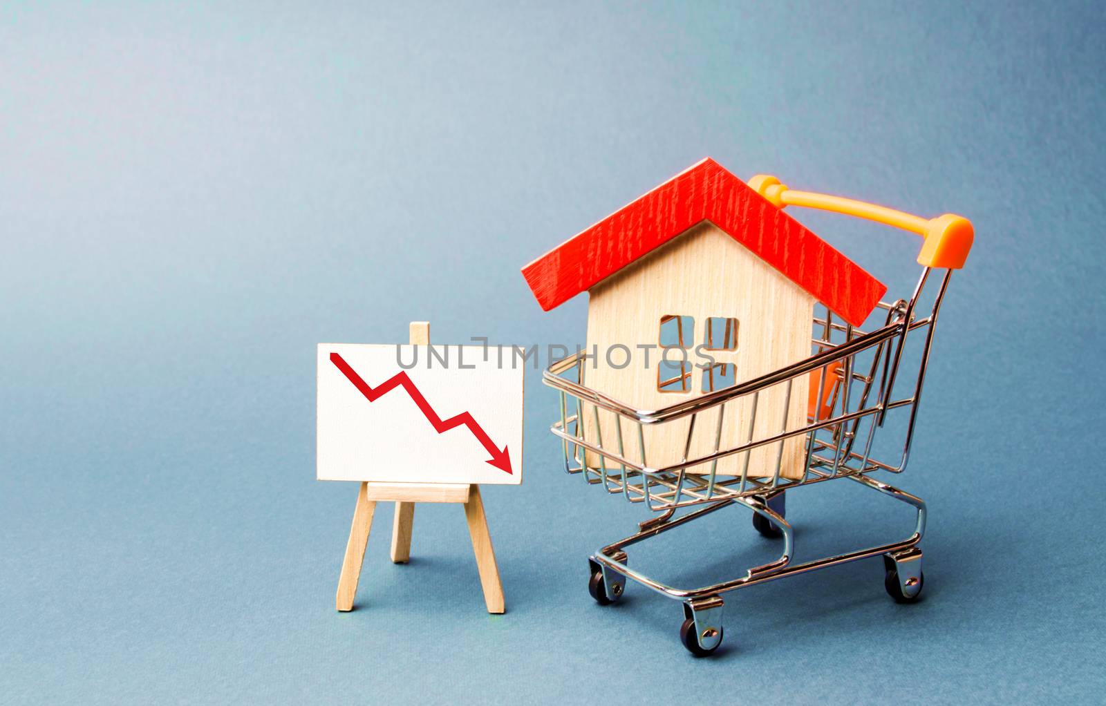 House in the shopping cart and a stand with red chart arrow down. The fall of the real estate market. concept of value or cost decrease. low liquidity and attractiveness. cheap rent or cost of buying. by iLixe48