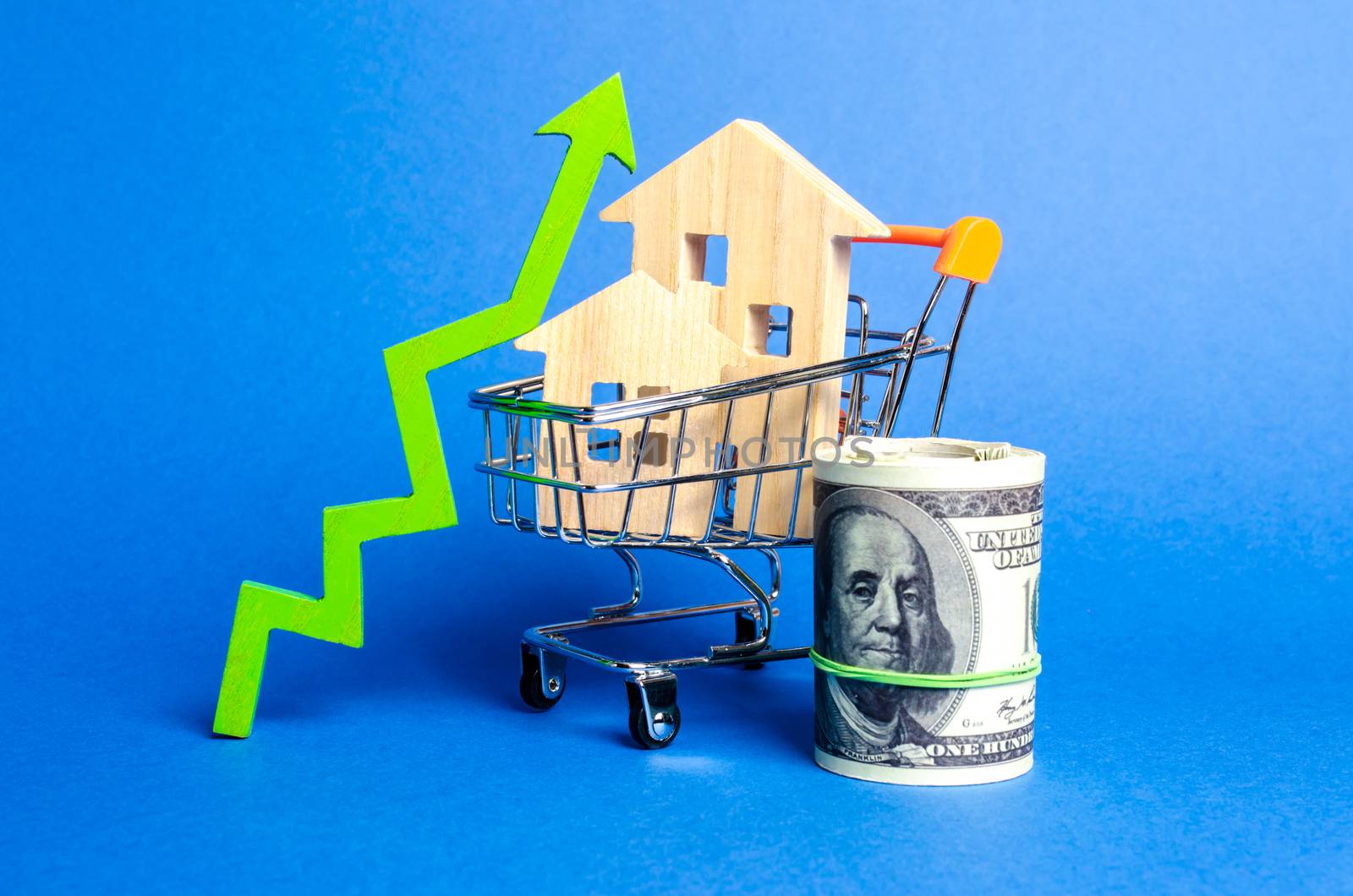 Two wooden houses in a trading cart and green arrow up and money bundle. Increasing cost and liquidity of real estate. Attractive investing. rising prices or renting. growth demand, rates of sales.