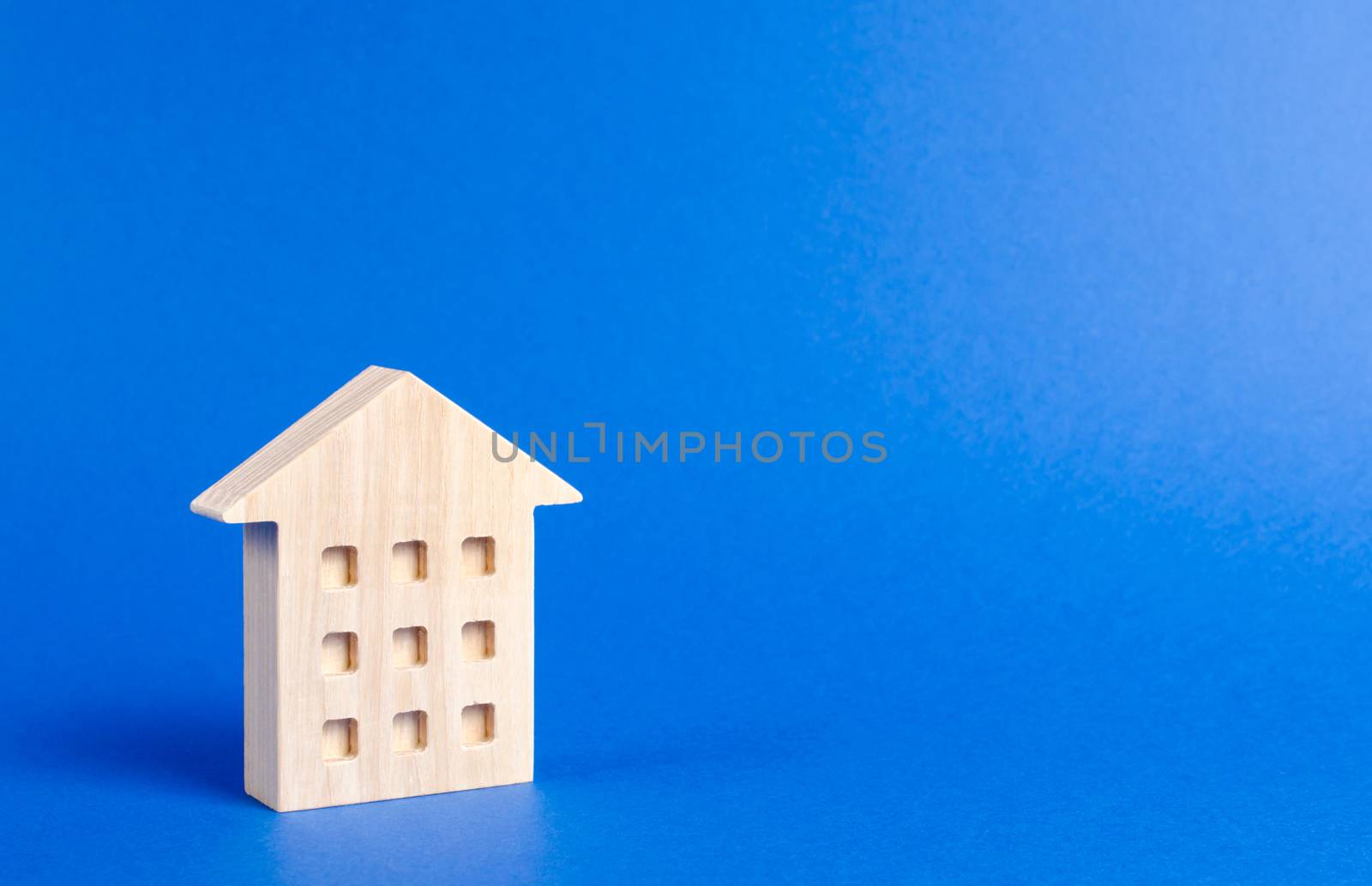 A wooden residential building stands on a blue background. The concept of buying and selling real estate, renting. Search for a house. Affordable housing, credit and loans. Investments. place for text