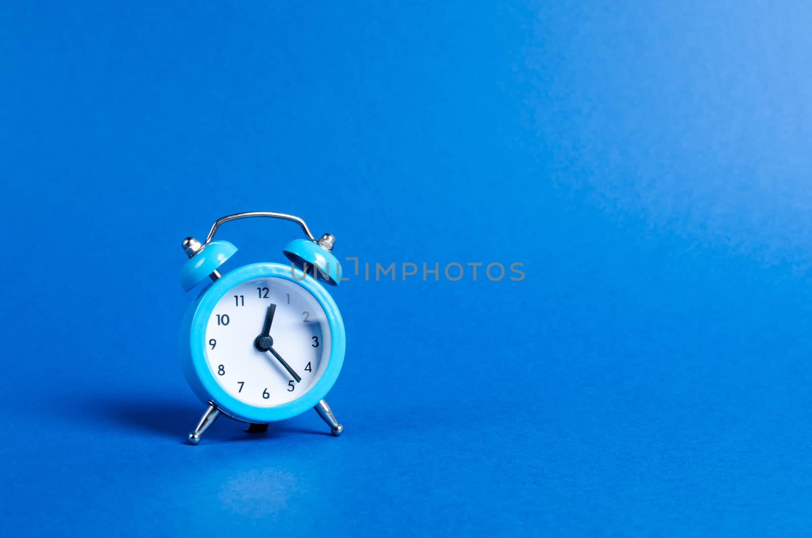 A blue alarm clock on a blue background. Limited offer and over time. Planning and discipline. waiting for a meeting. Punctuality. business planning. Life duration and health, increase your age.