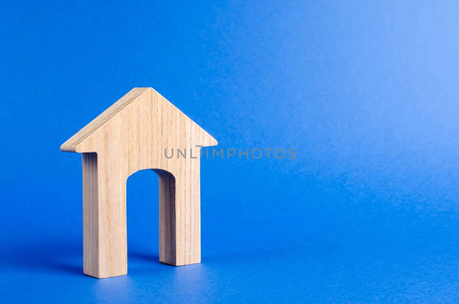 Wooden figure of a house with a large doorway on blue background. concept of buying and selling real estate, rent, investment. Home, Affordable housing, residential building. Construction buildings.