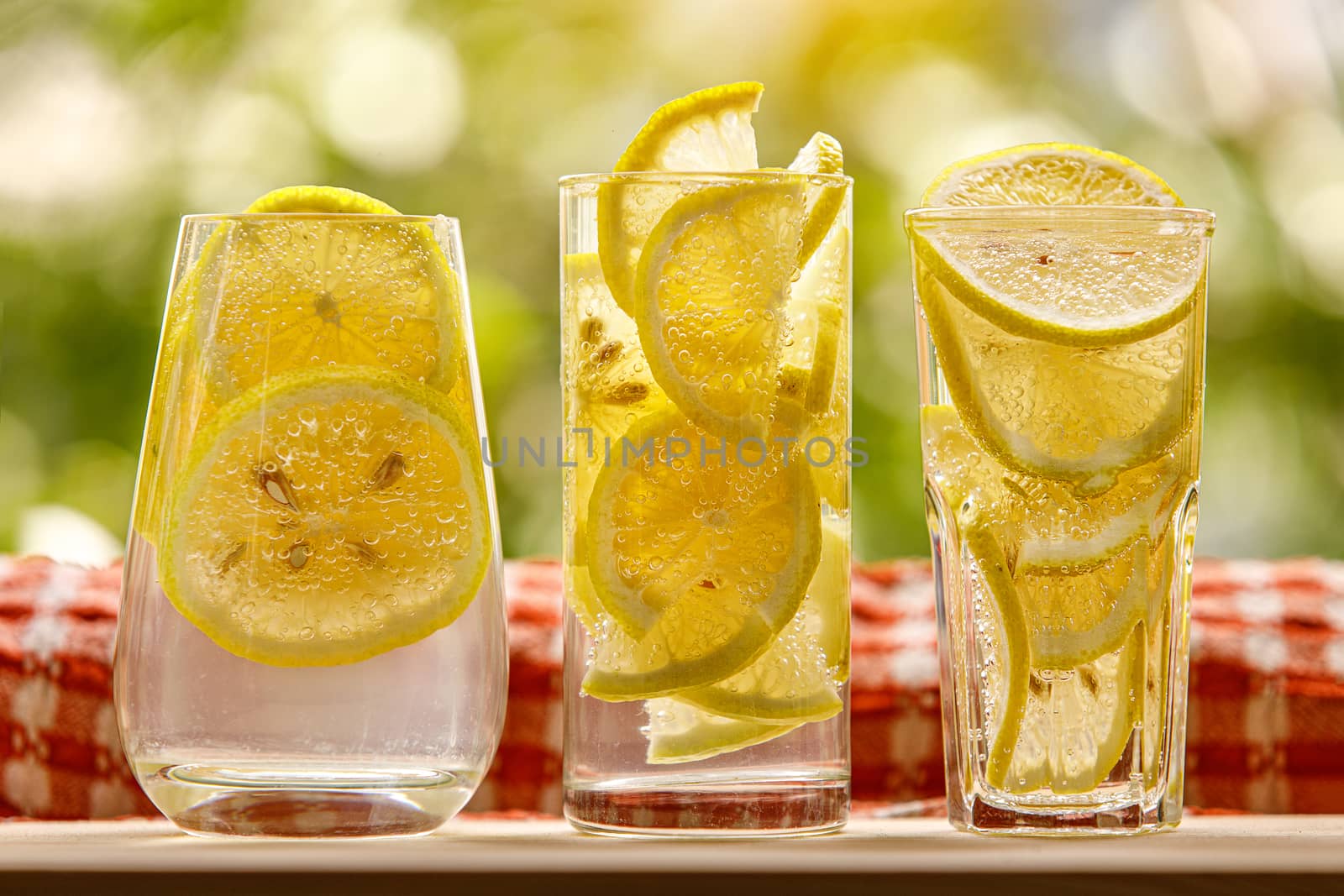 Glass of lemonade with lemon on sunny garden background. by 9parusnikov