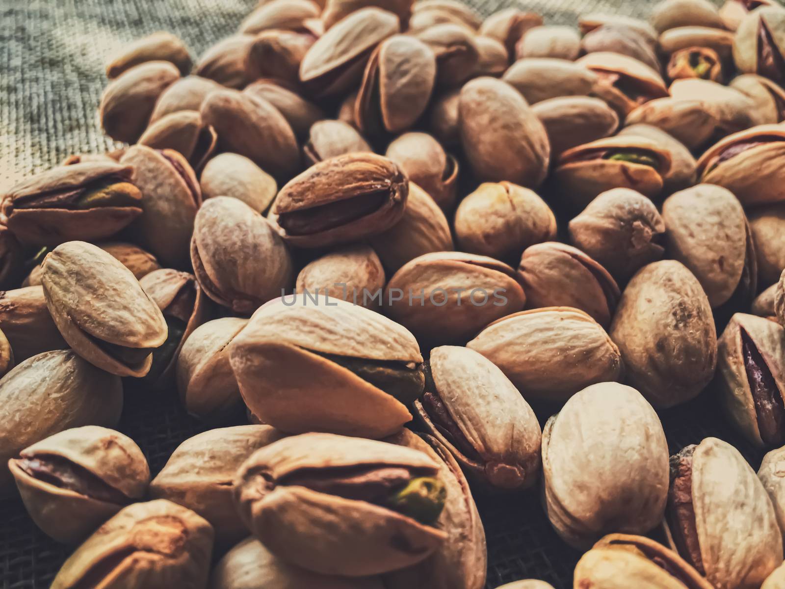 Pistachio nuts on rustic linen background, food and nutrition