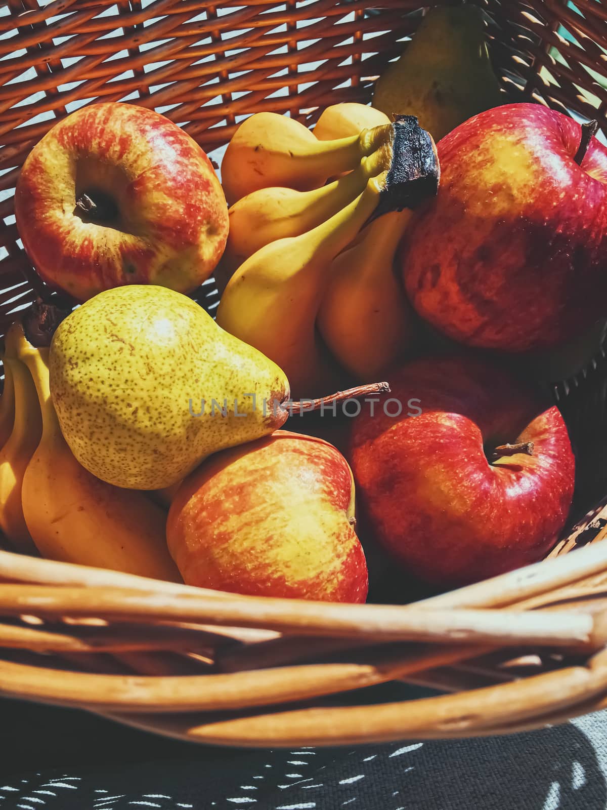 Organic apples, pears and bananas on rustic in a wicker basket by Anneleven