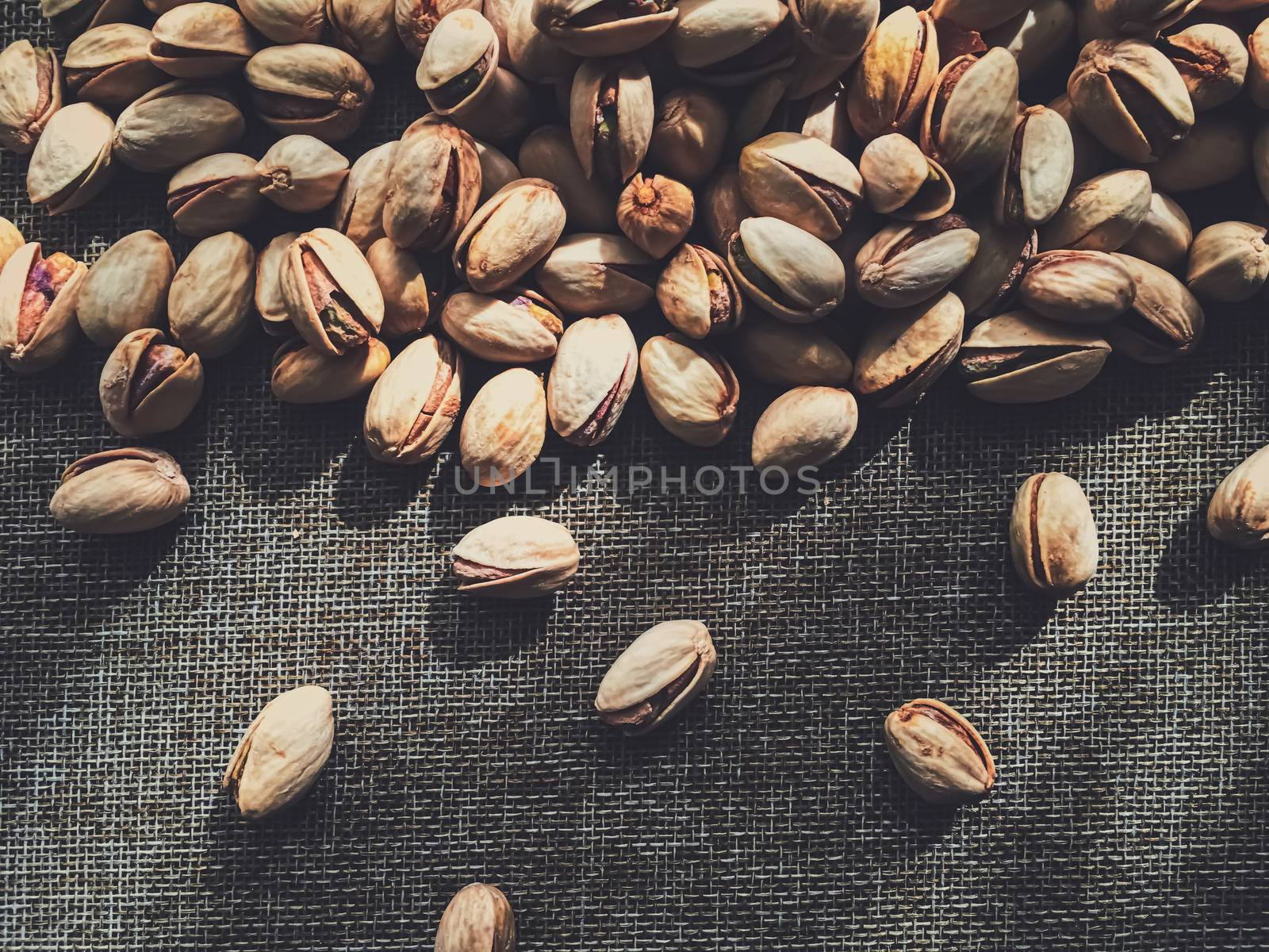 Pistachio nuts on rustic linen background by Anneleven