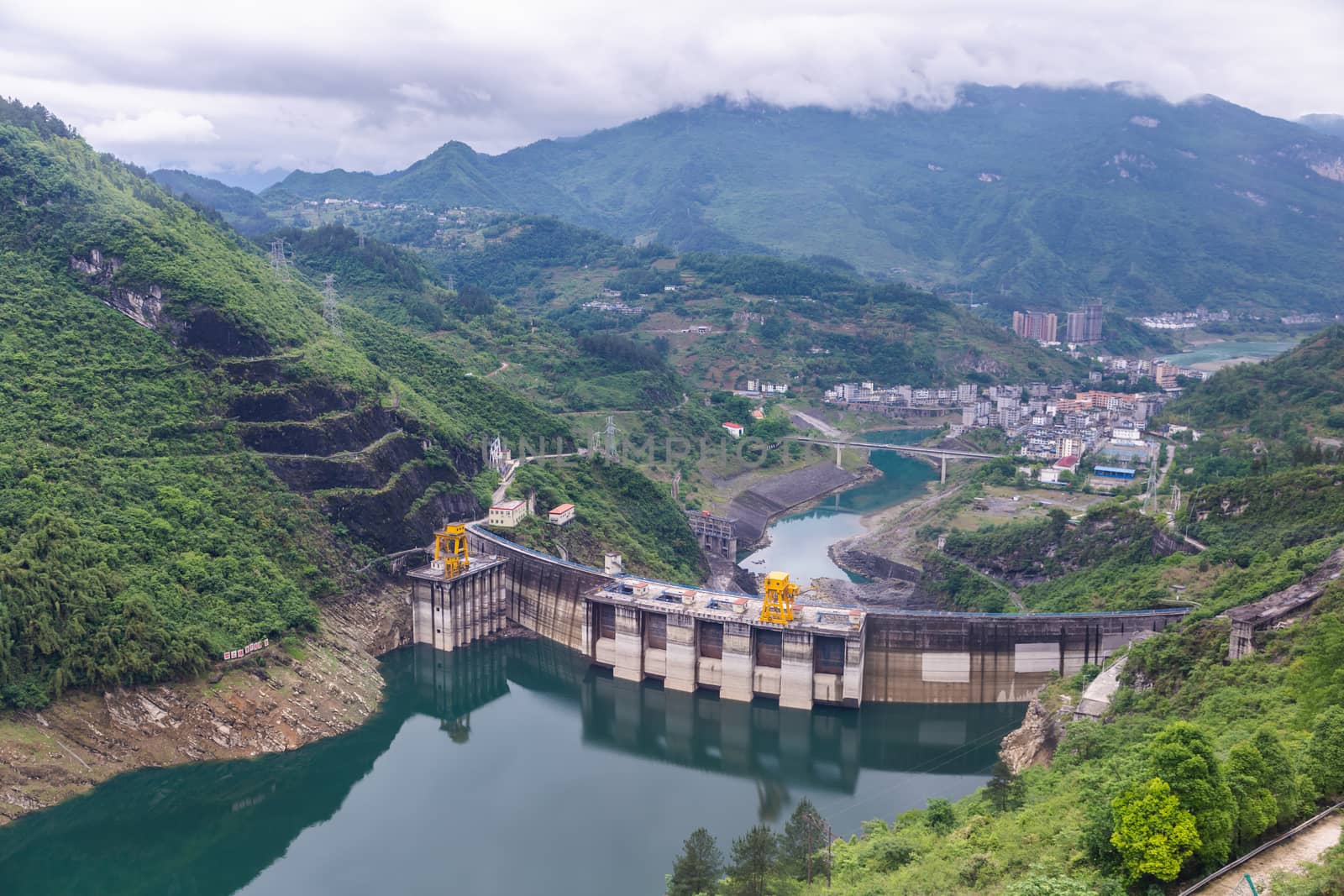 Dam wall and surrounding landscape at Wulong Dam in Chongqing, China. during summer with a low water level on a clear sunny day. by phanthit