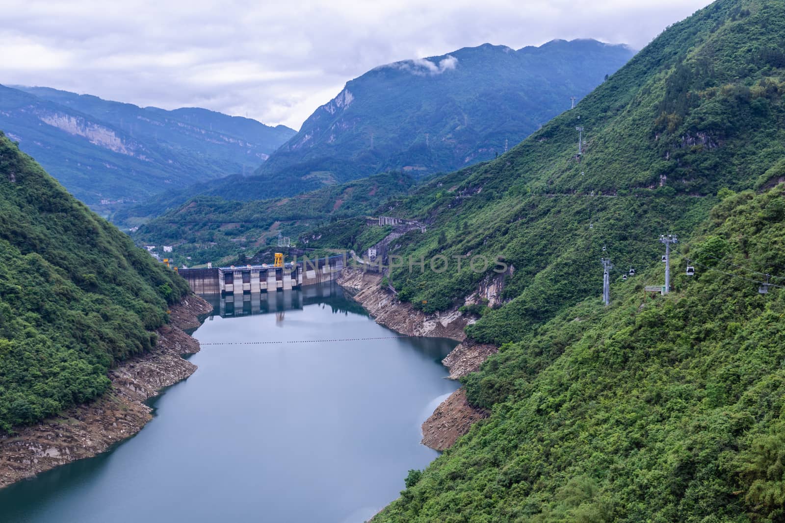 Dam wall and surrounding landscape at Wulong Dam in Chongqing, China. during summer with a low water level on a clear sunny day. by phanthit