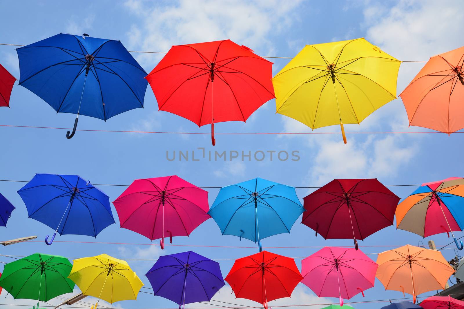 Colorful umbrellas background. Coloruful umbrellas urban street decoration. Hanging Multicoloured umbrellas over blue sky.