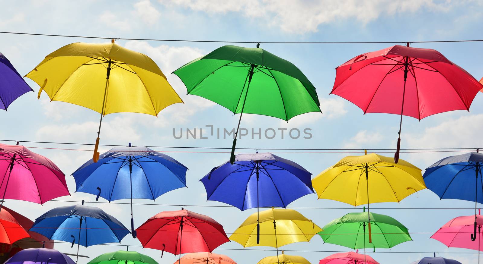 Colorful umbrellas background. Coloruful umbrellas urban street decoration. Hanging Multicoloured umbrellas over blue sky.