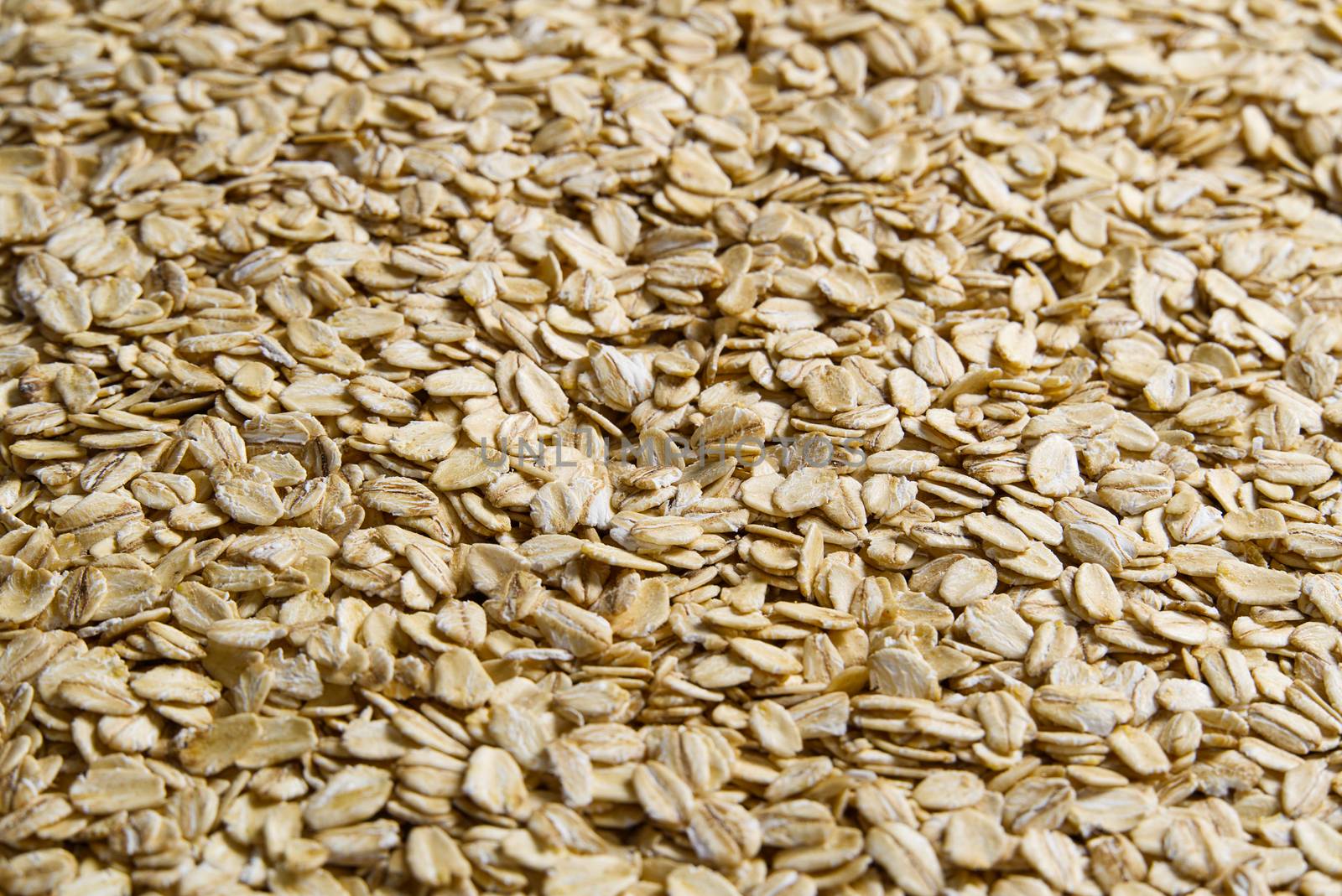 Oatmeal flakes close up as background. Close up of porridge oats as background or texture. Diet and healthy nutrition. by PhotoTime