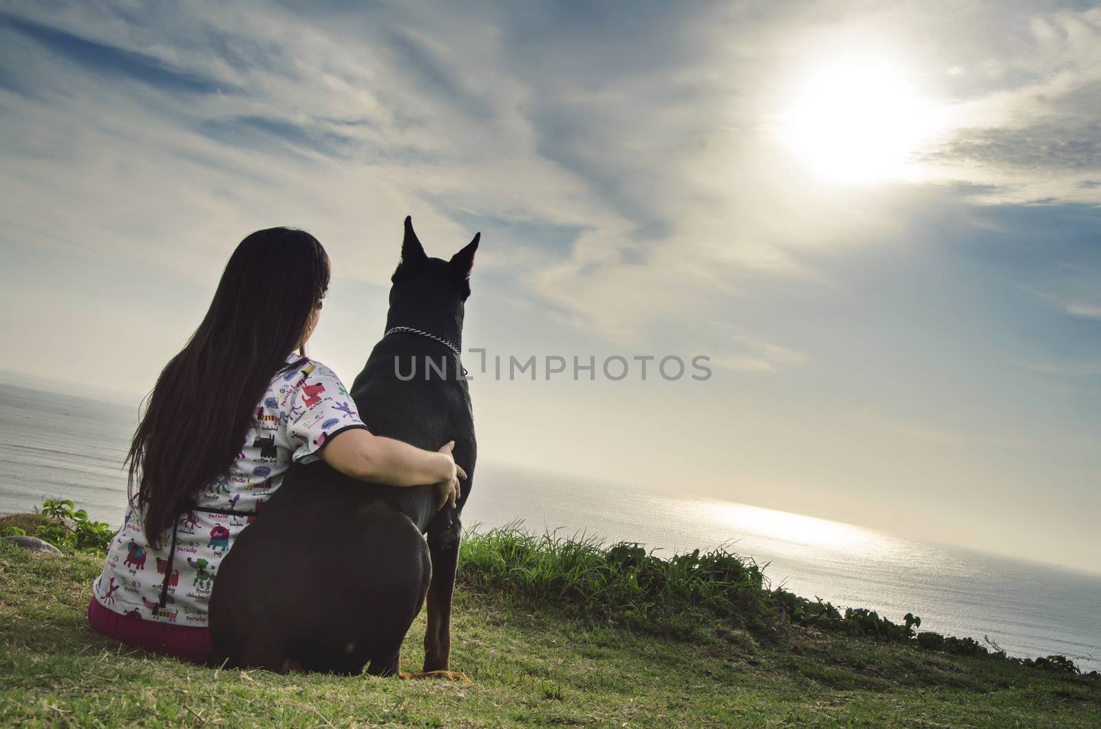A woman and her dog watching the sunset