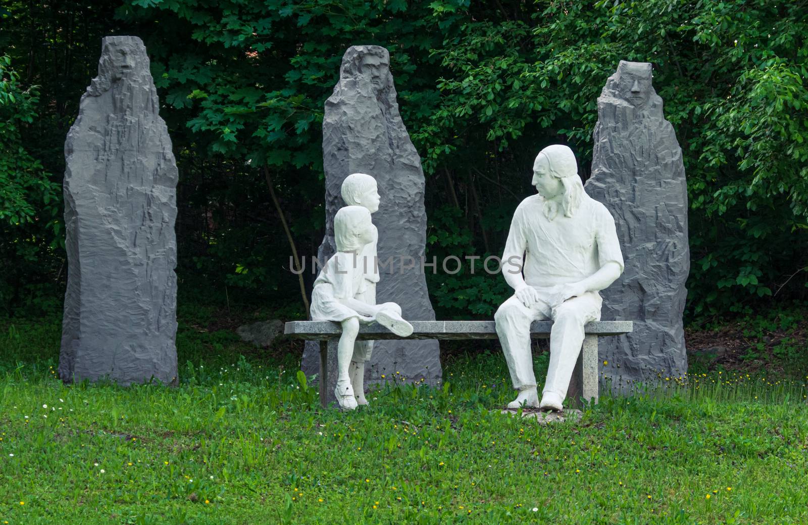 Statue of Nikolaus Ludwig, Reichsgraf von Zinzendorf und Pottendorf teaching children while sitting on a stone bench in a park.