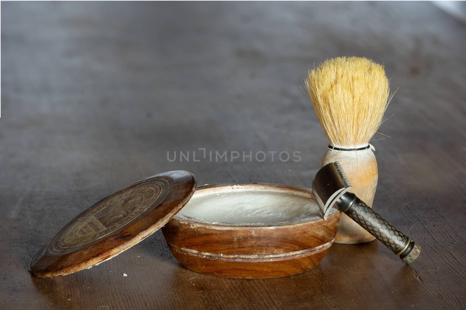 wooden bowl of shaving soap with razor and shaving brush on wooden table surface with copy space; barber equipment