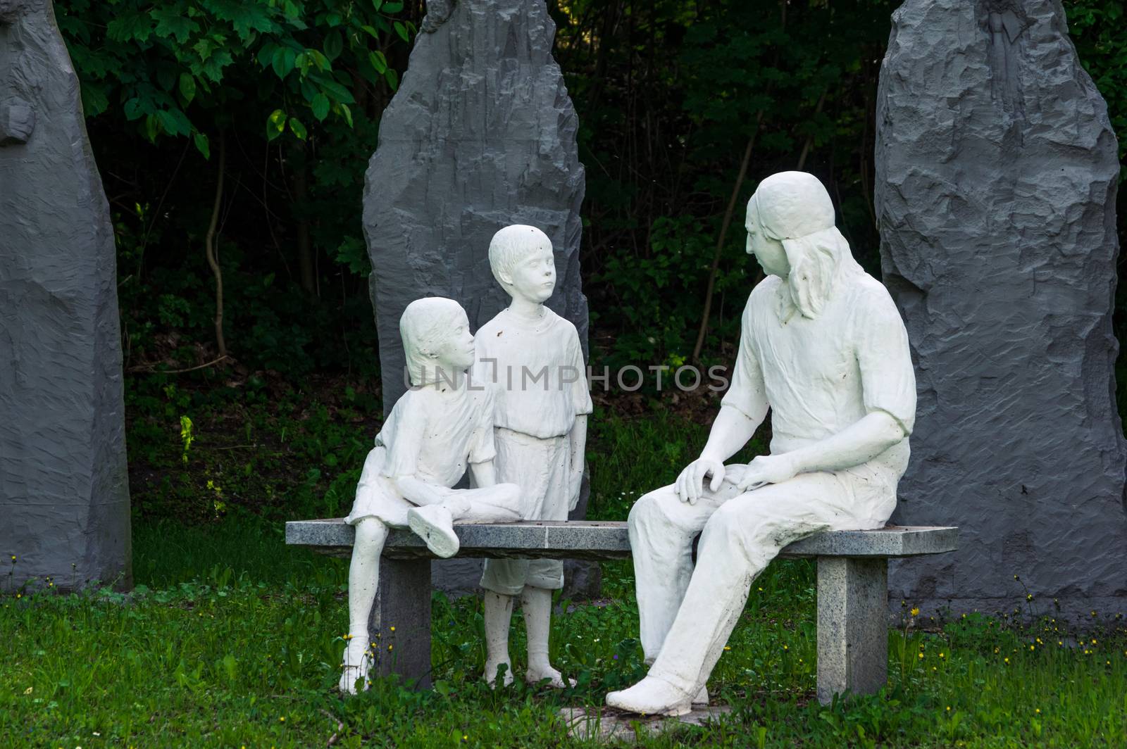 Statue of Nikolaus Ludwig, Reichsgraf von Zinzendorf und Pottendorf teaching children while sitting on a stone bench in a park.
