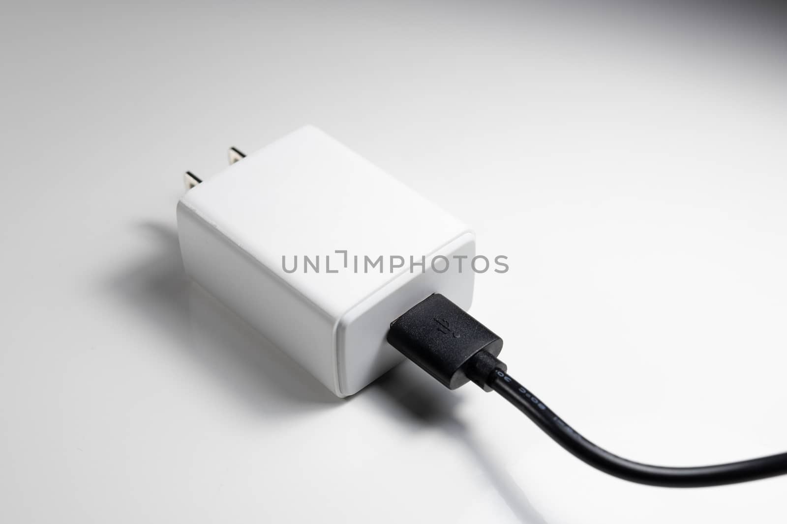 White charger adapter and black USB cable on a white background The concept of charging technology to power mobile phones