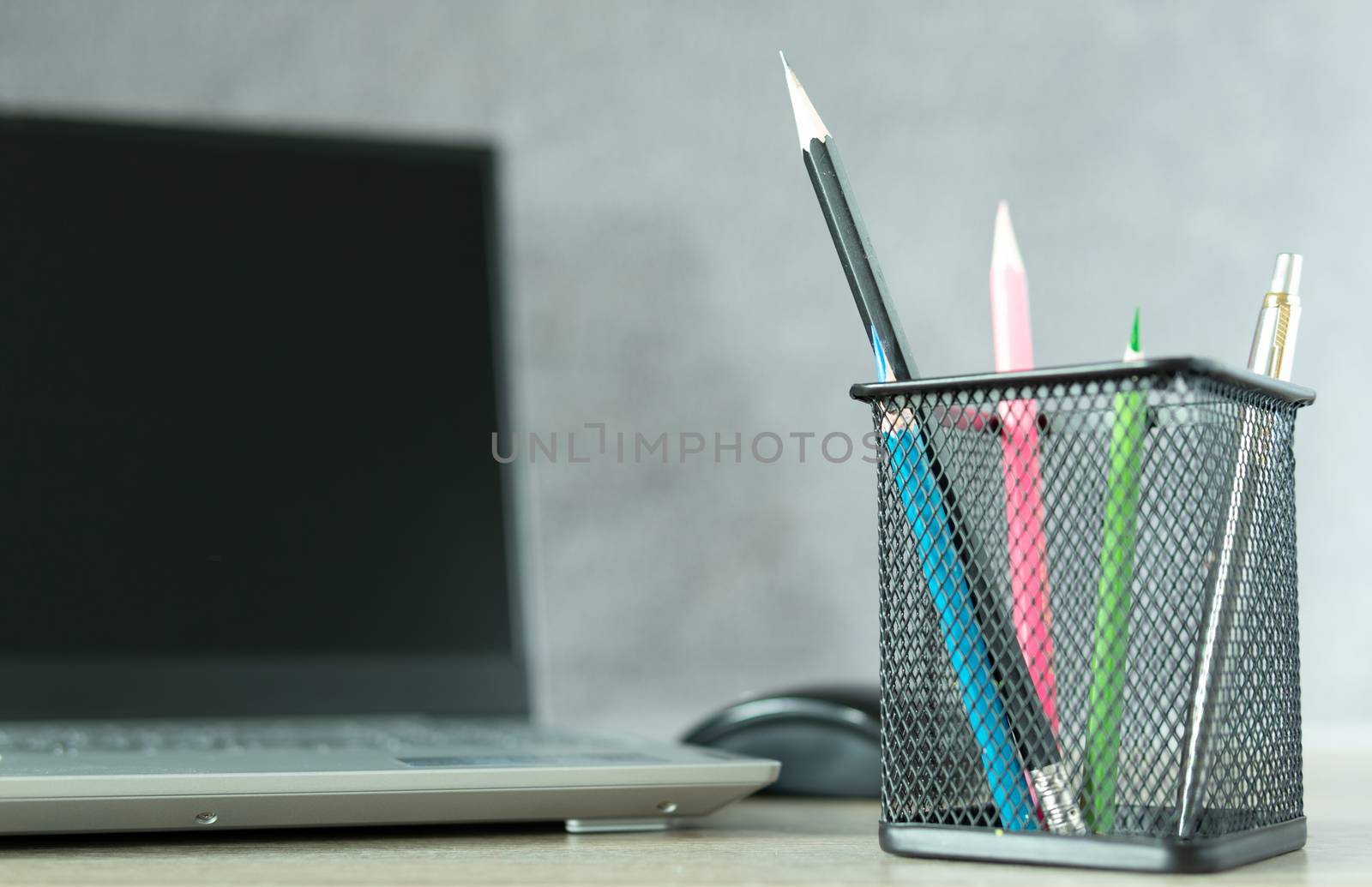 Black basket with blue pencil Ready to use with other colored pencils And notebook computers placed blurred behind on the desk, office equipment at work or at home. Future business concepts