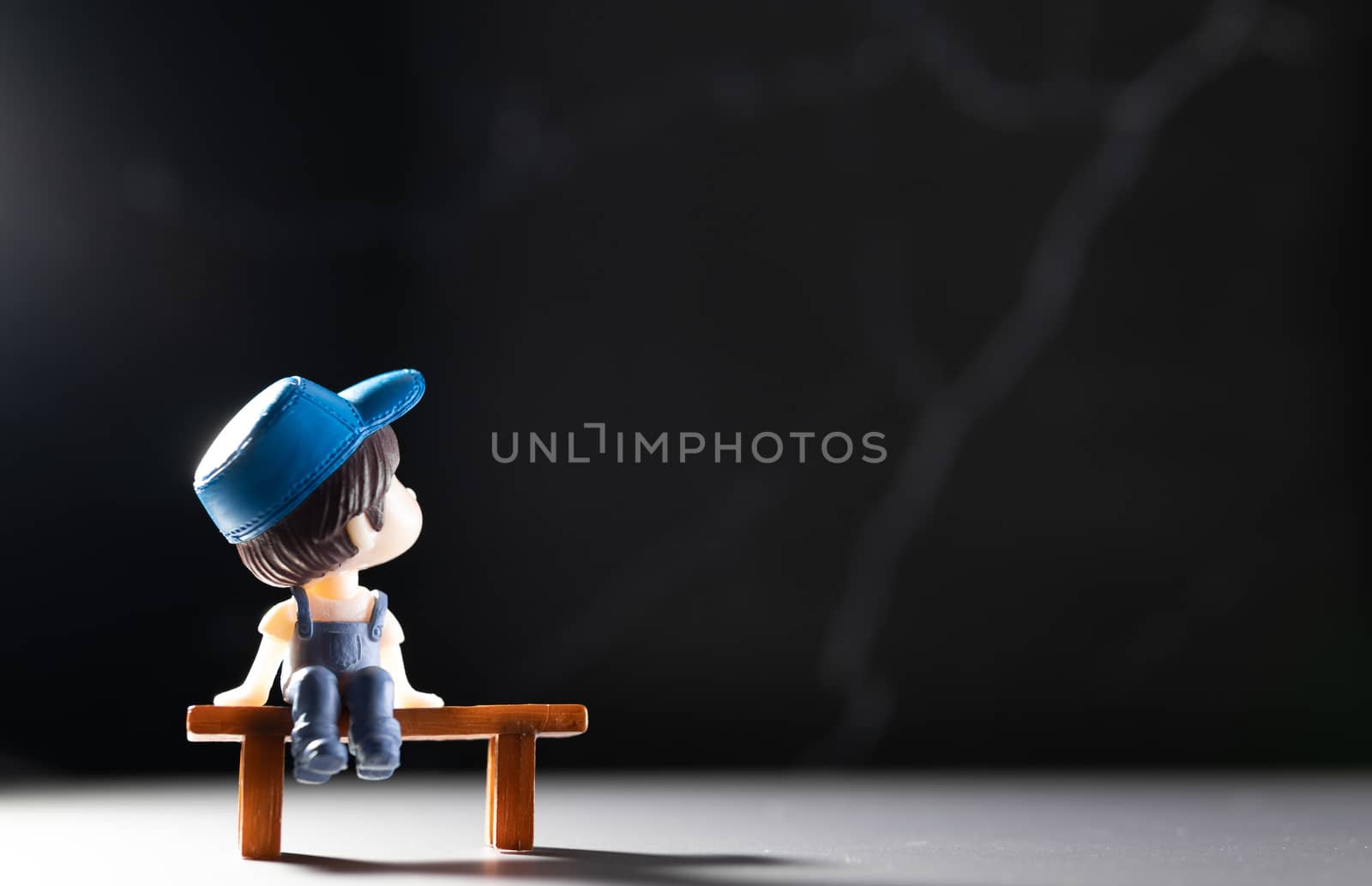 A small cartoon man sitting on a wooden table alone To wait or Demonstrated the idea of ​​a distant society to avoid the spread of coronary viruses or other contagious diseases