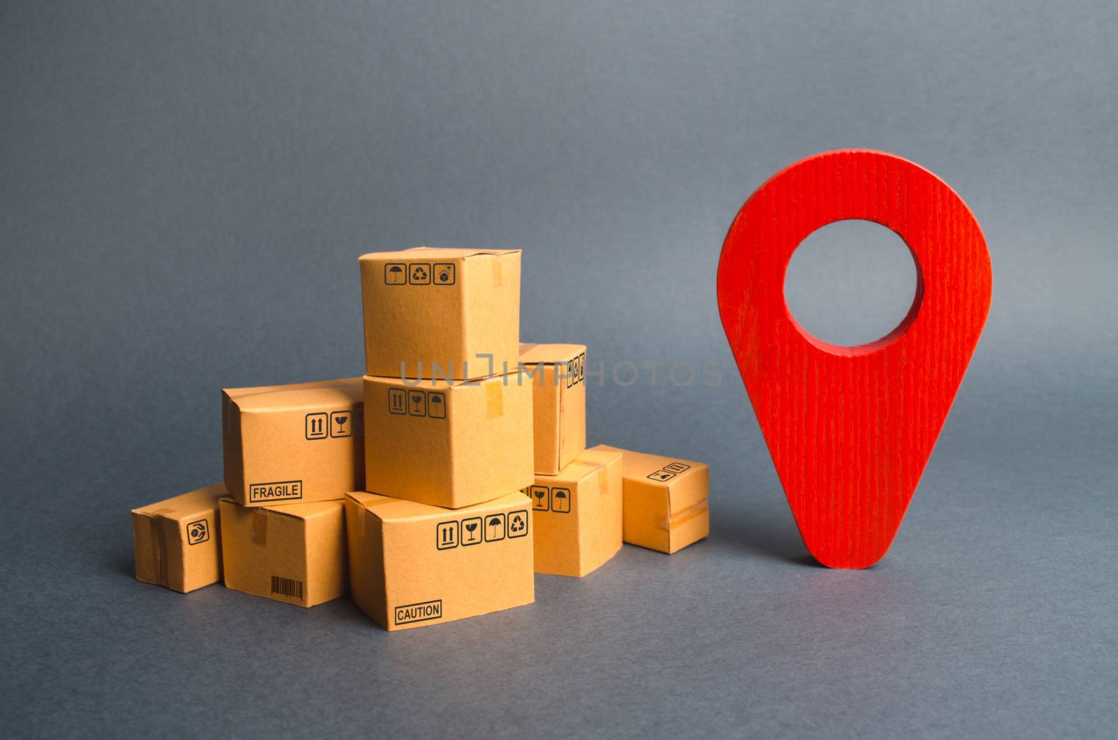 A pile of cardboard boxes and a red position pin. Locating packages and goods. Algorithm for constructing a minimum route for the delivery of orders. Tracking parcels via the Internet. by iLixe48
