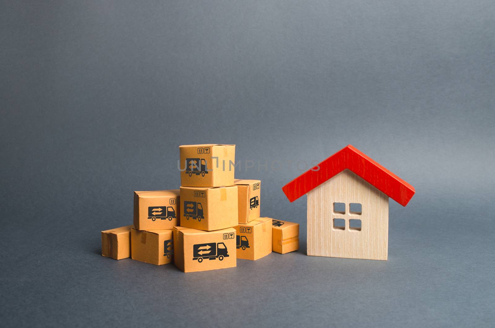 A pile of cardboard boxes and a wooden house. Concept of moving to another house or city. Property transportation. Freight shipping, delivery and installation. The beginning of a new stage of life