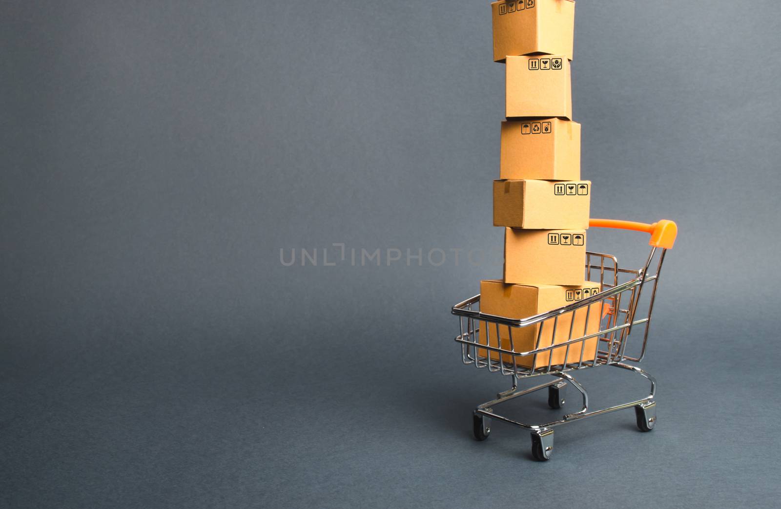 High tower of cardboard boxes on a supermarket trolley. concept of shopping in online store. E-commerce, sales and sale of goods through online trading platforms. Consumer society. Purchasing power