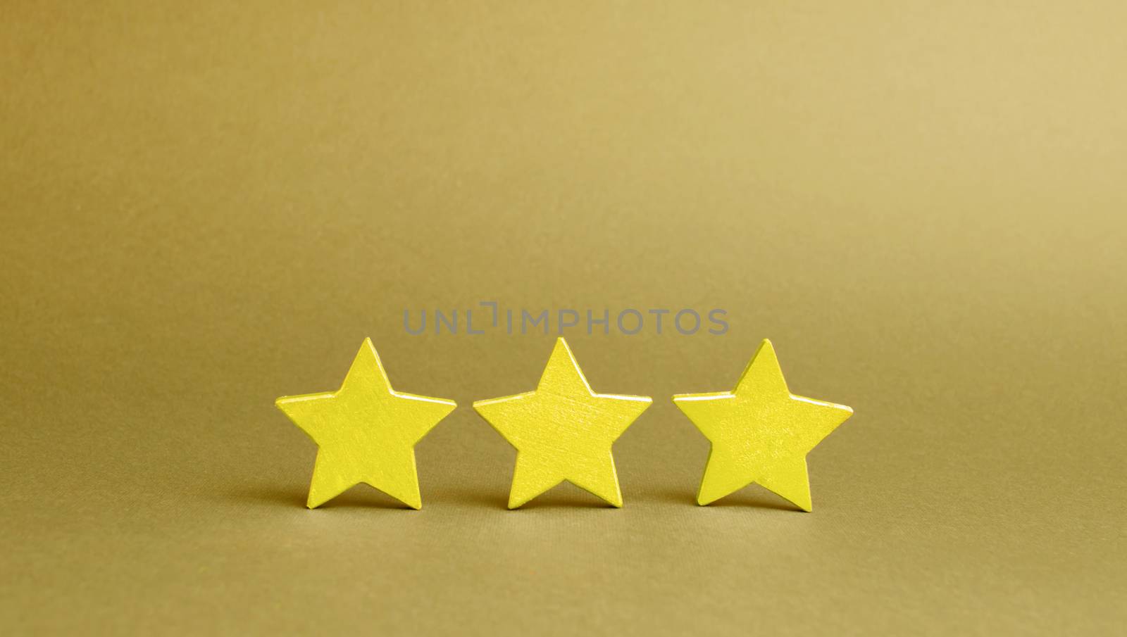 Three golden stars on a yellow background. Quality service, buyer choice. Success in business. The concept of rating and evaluation. The rating of the hotel, restaurant, mobile application.