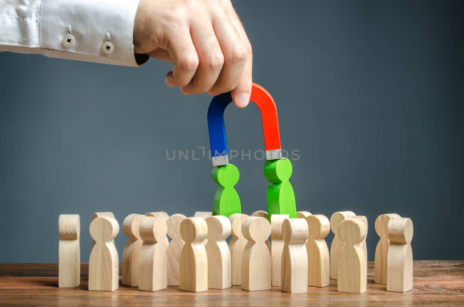 Businessman with a magnet pulls green figures of people out of the crowd. Recruiting new workers. Formation of a new business team of applicants. Search talented workers with great career potential by iLixe48