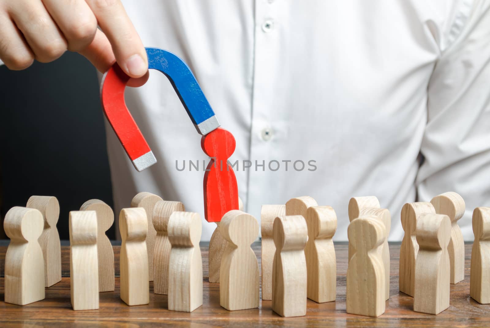 businessman pulls out a red figure of a man from the crowd with the help of a magnet. toxic, uncompetent worker. Increase team efficiency, productivity. leader manages the business and forms a team.