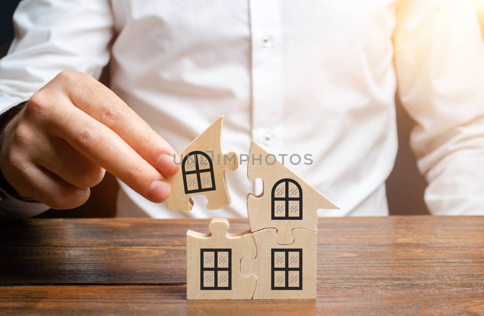 A man collects a house of puzzles. Construction of your own residential building. Mortgage loan, residential expansion and improvement of living conditions. Creating a family. The concept of stability