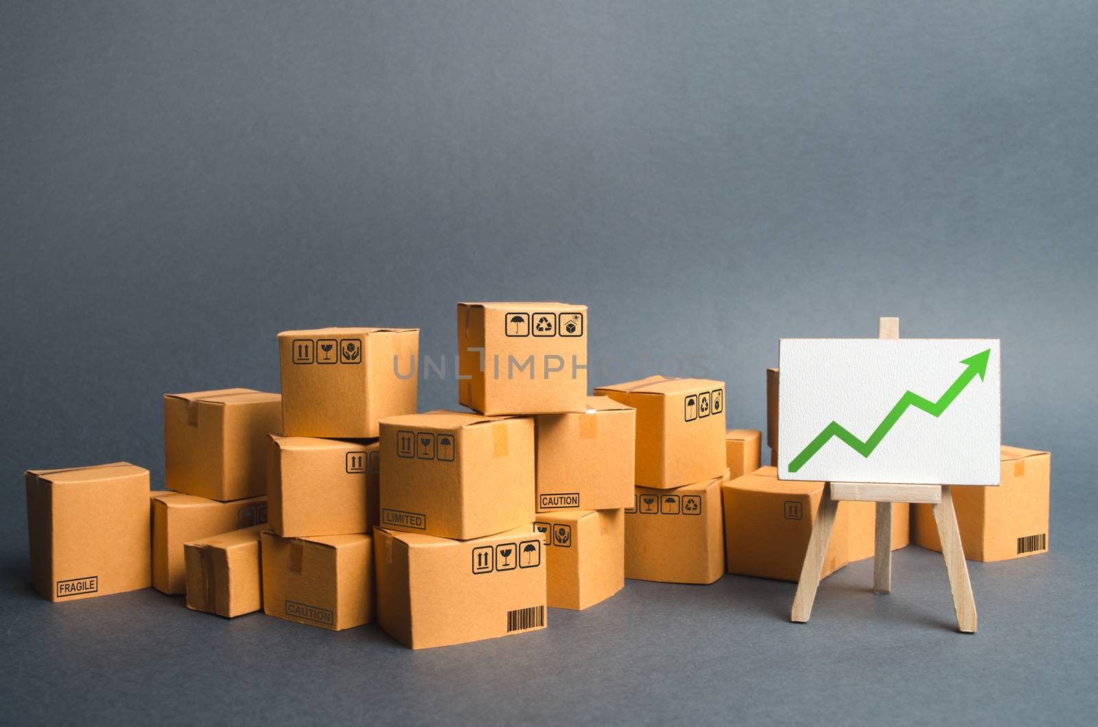 Lots of cardboard boxes and a stand with a green up arrow. rate growth of production of goods and products, increasing economic indicators. Increasing consumer demand, increasing exports or imports. by iLixe48