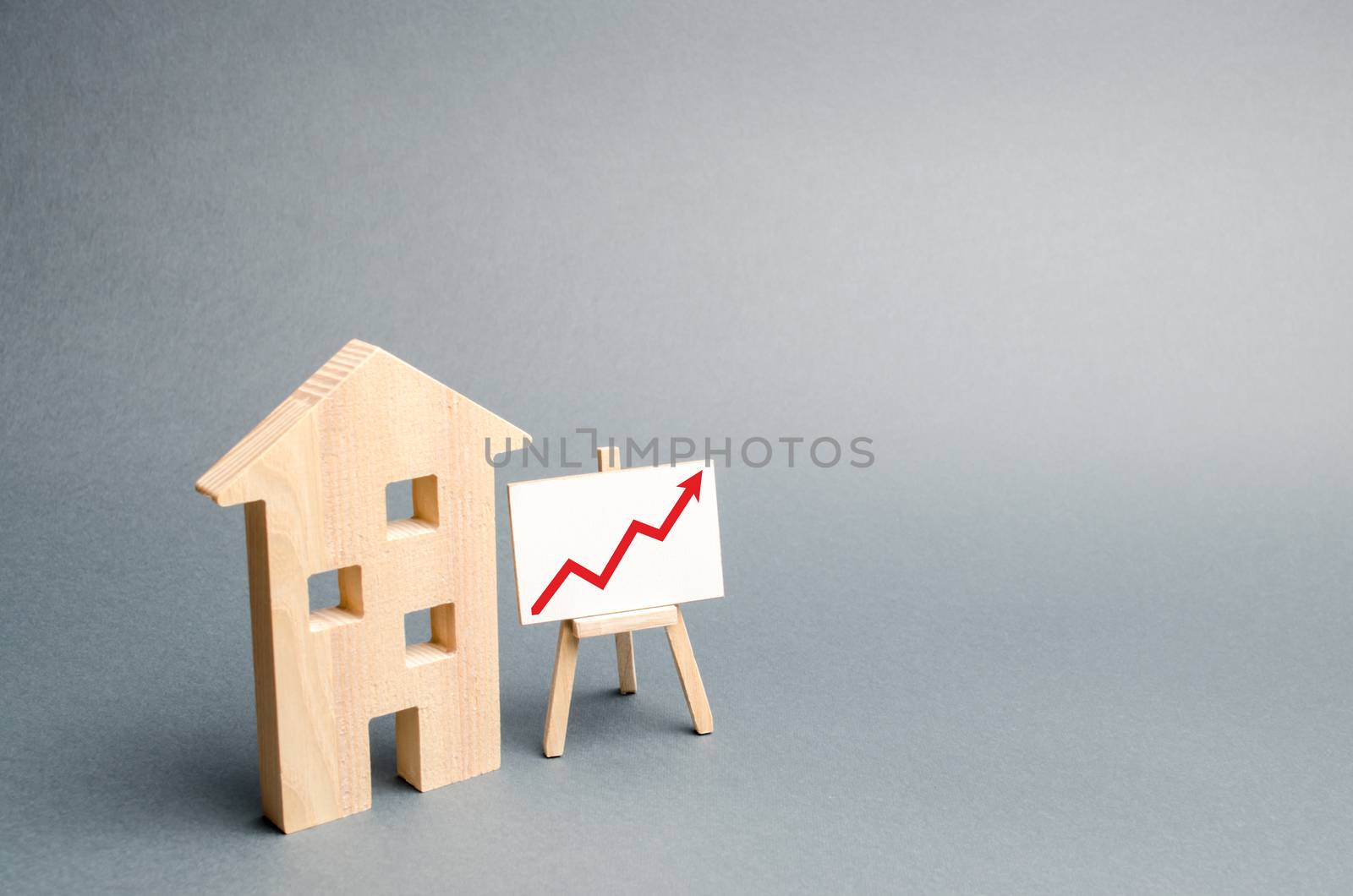 Wooden house and stand with red arrow up. Growing demand for housing real estate. growth of the city and its population. Investments. rising prices for housing or rent. Rising costs. Selective focus by iLixe48