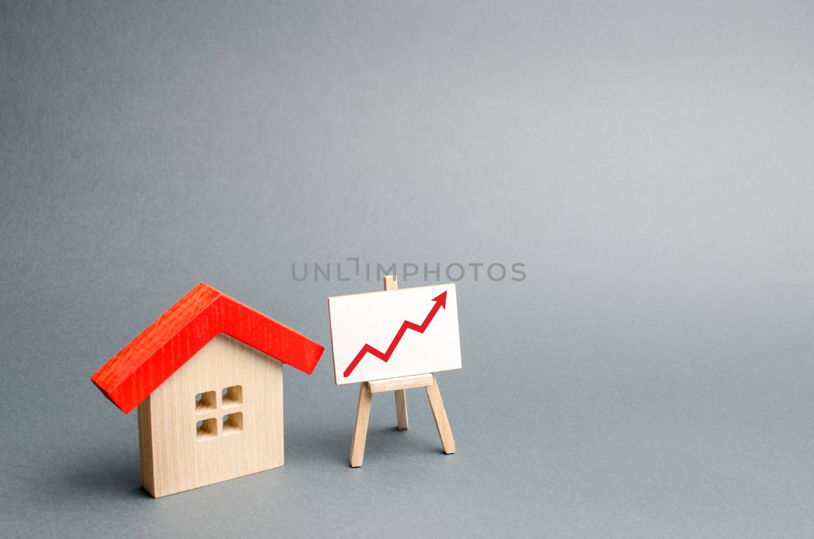 Wooden house and stand with red arrow up. Growing demand for housing and real estate. The growth of the city and its population. Investments. concept of rising prices for housing. Selective focus