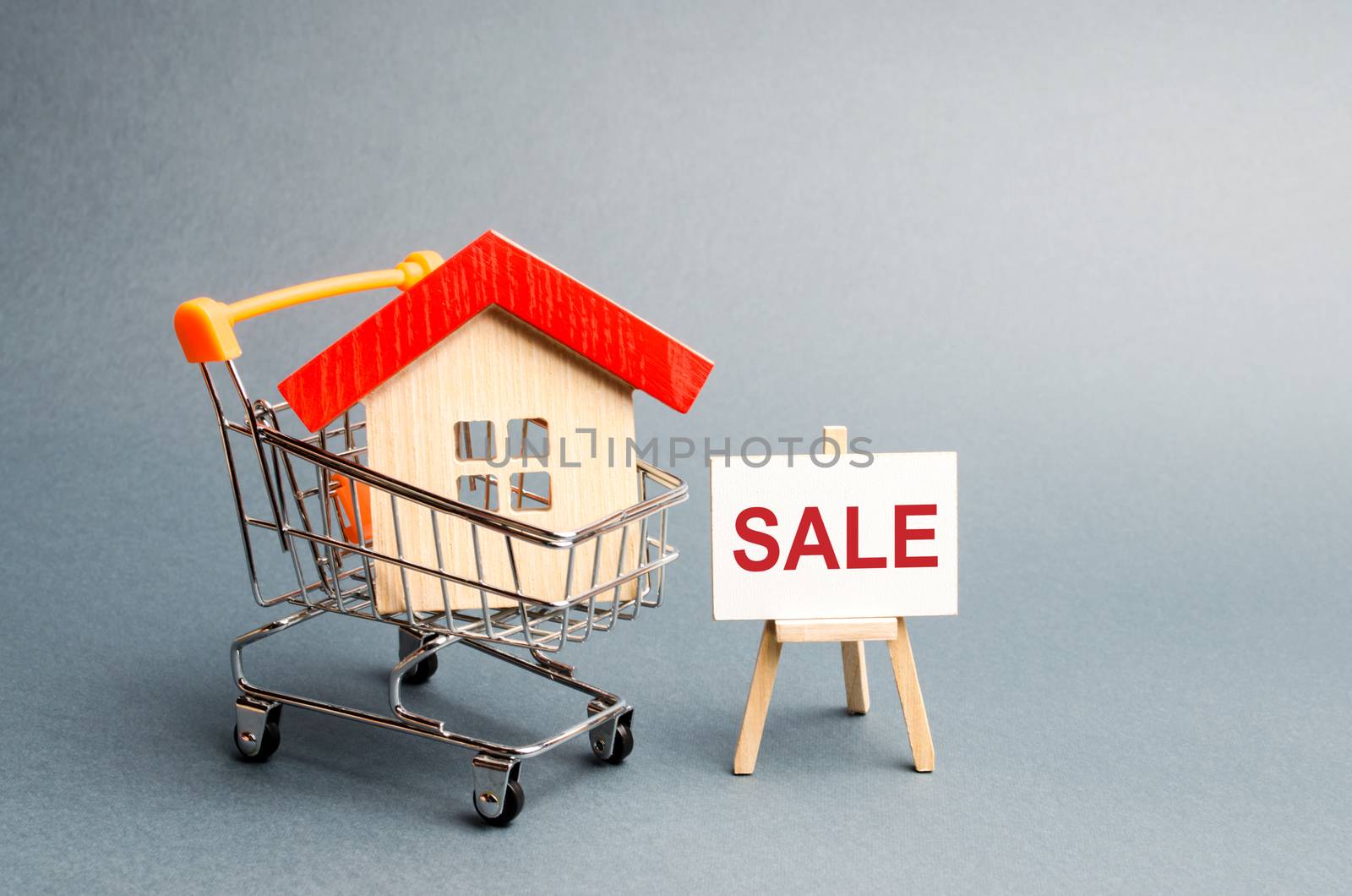 Supermarket cart with houses and a Sale Poster. The concept of selling a home, real estate services or buying from the owner. Buying and selling real estate, property, apartments. Selective focus by iLixe48