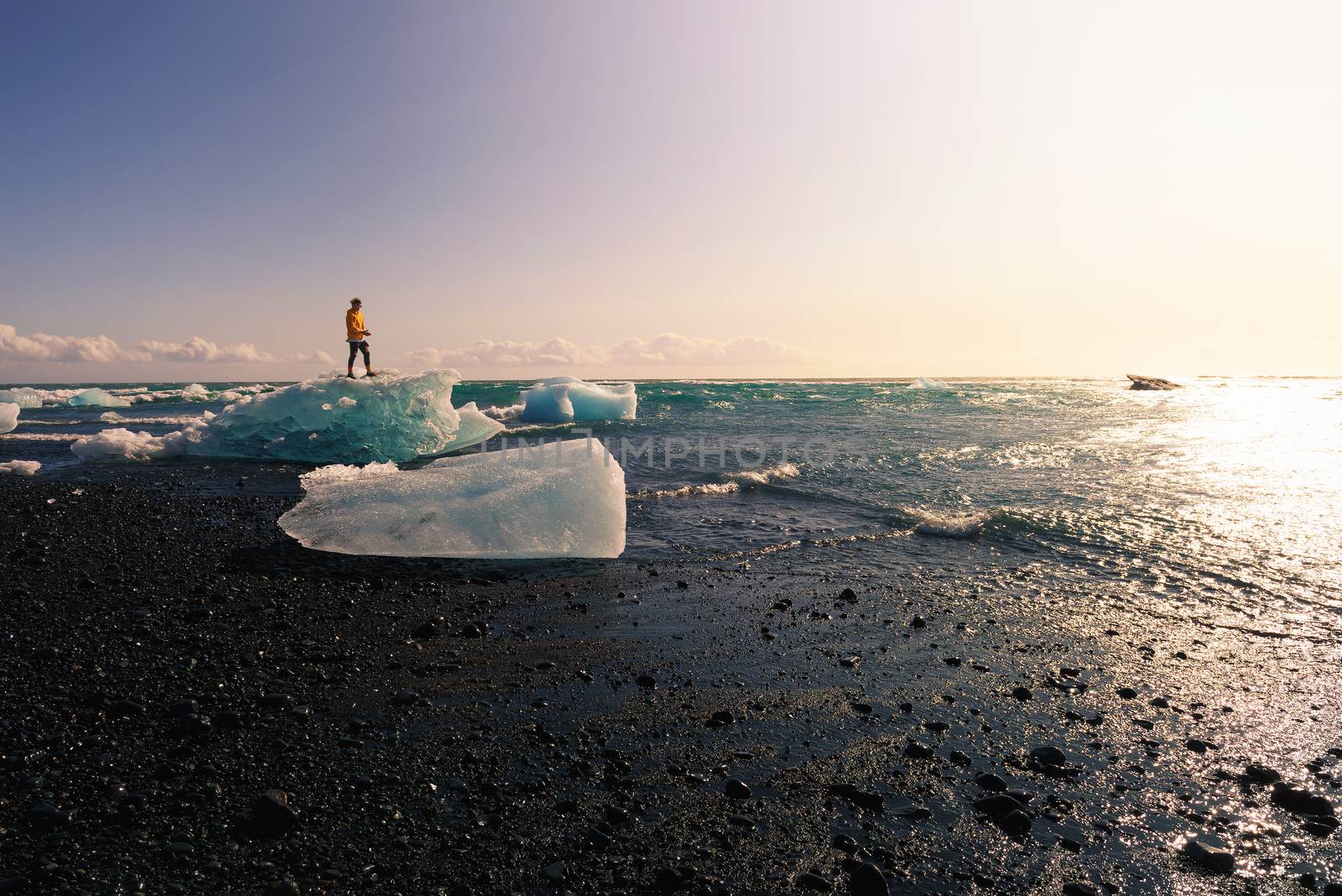 Tourist standing on an iceberg at the Diamond Beach, Iceland by nickfox