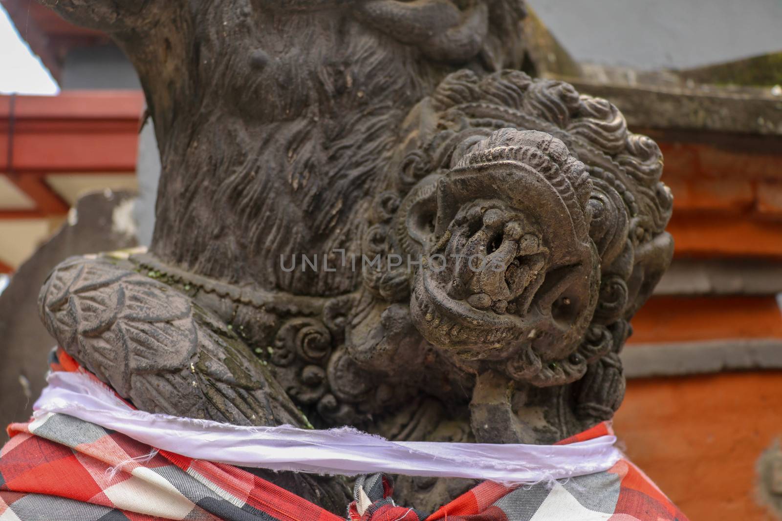 A close up on a guardian figure next to a Hindu temple on Bali, Indonesia. A bricked entrance gate to a Hindu temple on Bali. Traditional and historical site. Sculpture of a Balinese temple guardian.
