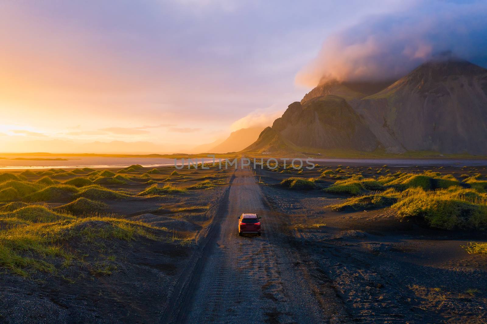 Gravel road at sunset with Vestrahorn mountain and a car driving, Iceland by nickfox